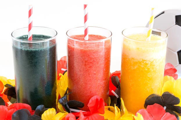 Deutschland-Dessert Drei bunte Smoothies in Glaesern mit gestreiften Strohhalmen, die gemeinsam die Deutschland-Flagge darstellen sollen.
