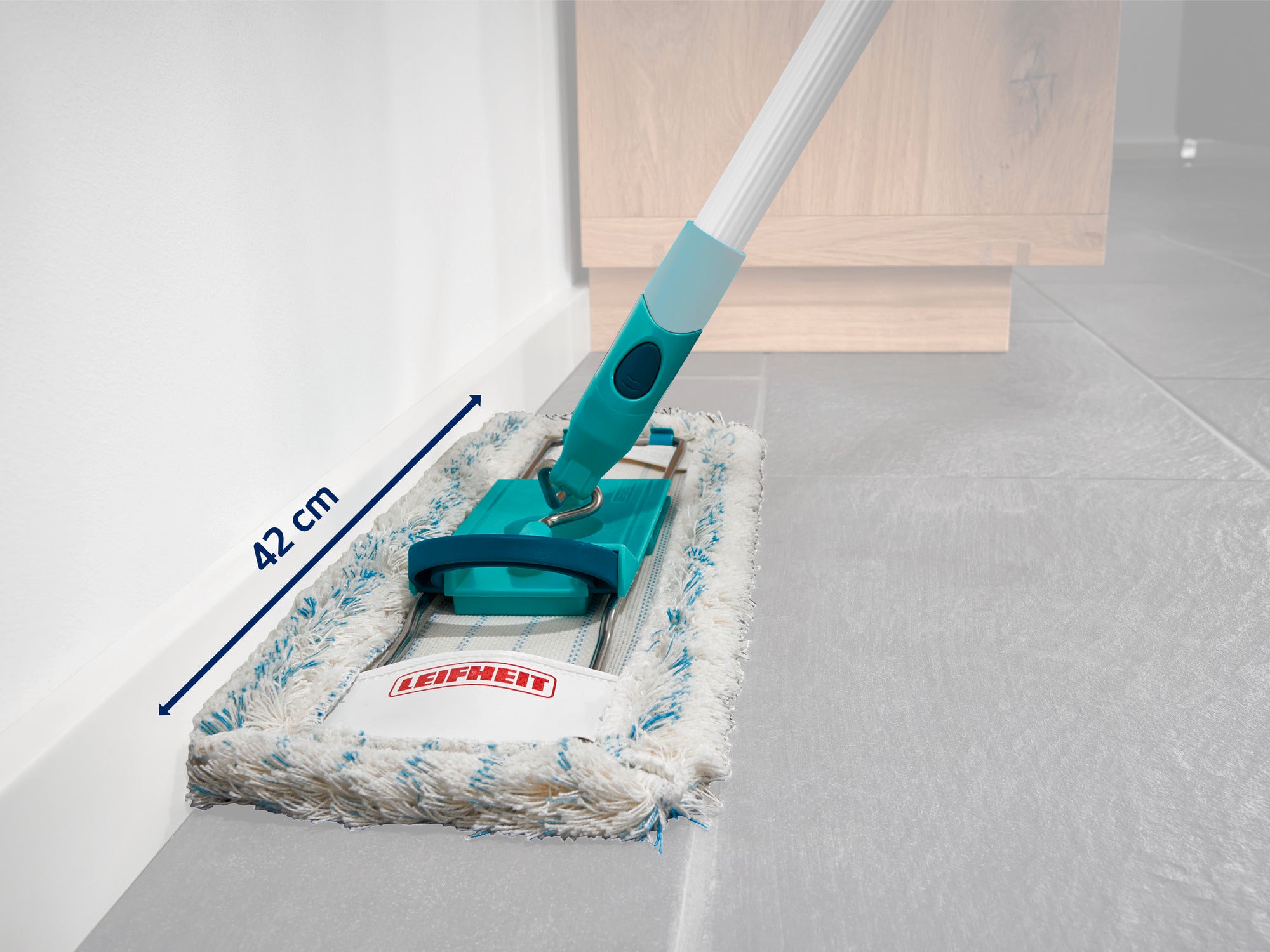 Ein Reinigungsgerät mit einem 42 cm breiten Wischkopf wird auf einem grauen Boden verwendet. Der Griff ist türkisfarben und das Gerät trägt die Aufschrift "Leifheit".