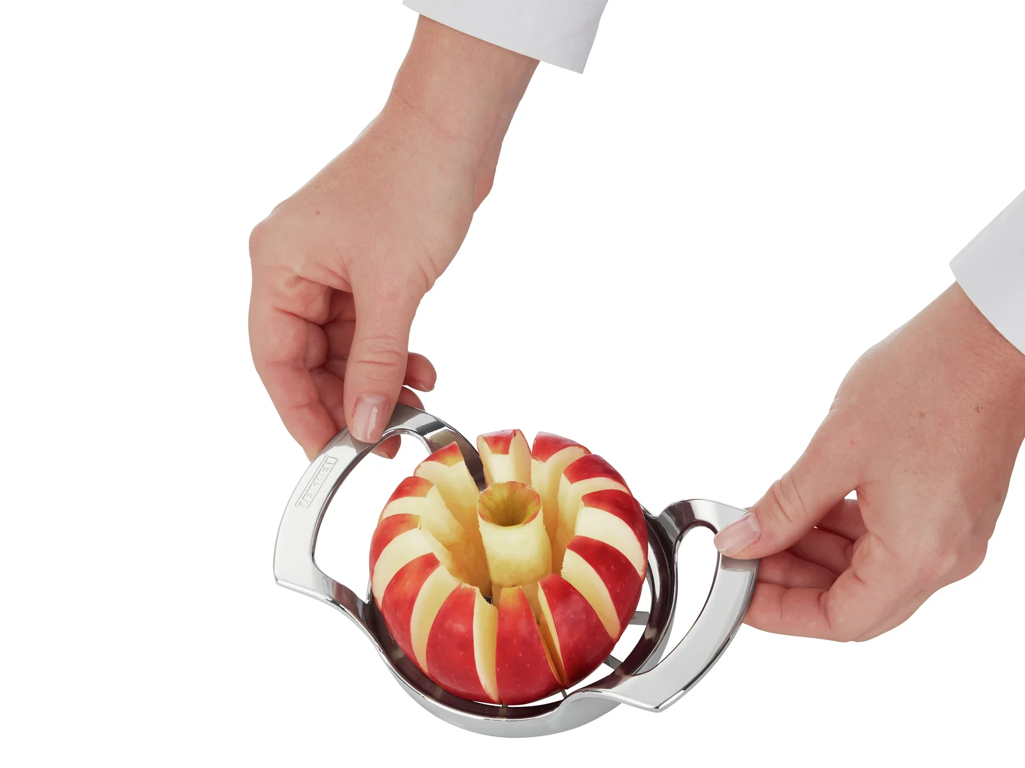 Krajalnica do jabłek jest używana do krojenia jabłek na równe plasterki. Dwie ręce trzymają krajalnicę, podczas gdy jabłko znajduje się pośrodku.