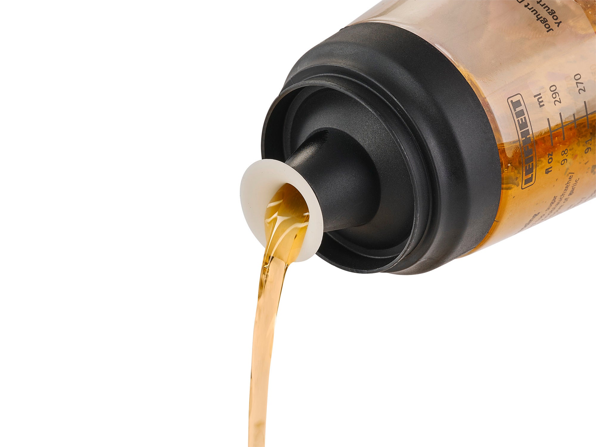 Ein Salat-Dressing-Shaker wird in Aktion gezeigt. Eine goldene Flüssigkeit wird aus dem Shaker gegossen, was die praktische Anwendung und Funktionalität des Produkts verdeutlicht.