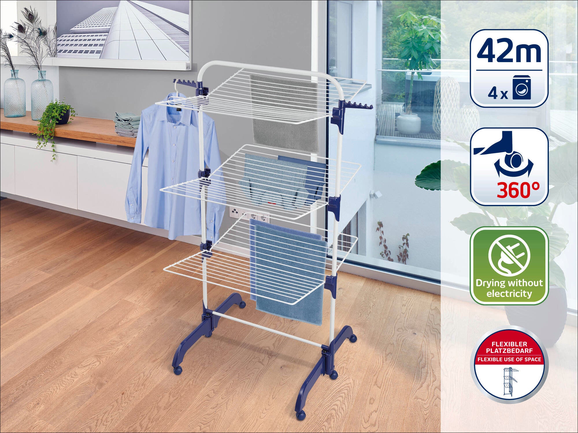 A tower dryer stands in a modern room with wooden floors. It offers 42 metres of drying length, is flexible and space-saving and requires no electricity. Ideal for efficient drying.