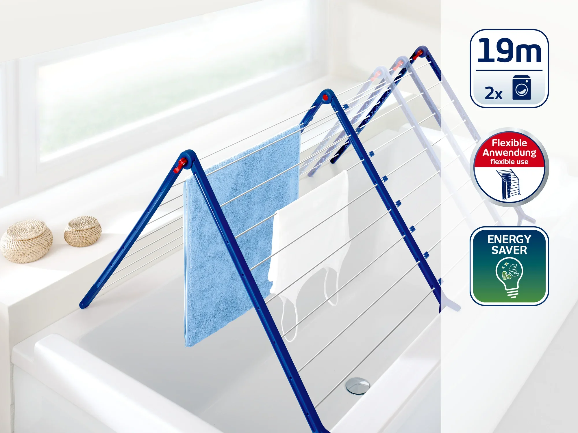 Suszarka nawannowa z niebieską ramą stoi na wannie. Oferuje 19 metrów długości suszenia i może być używana elastycznie. Energooszczędna i idealna do małych pomieszczeń.