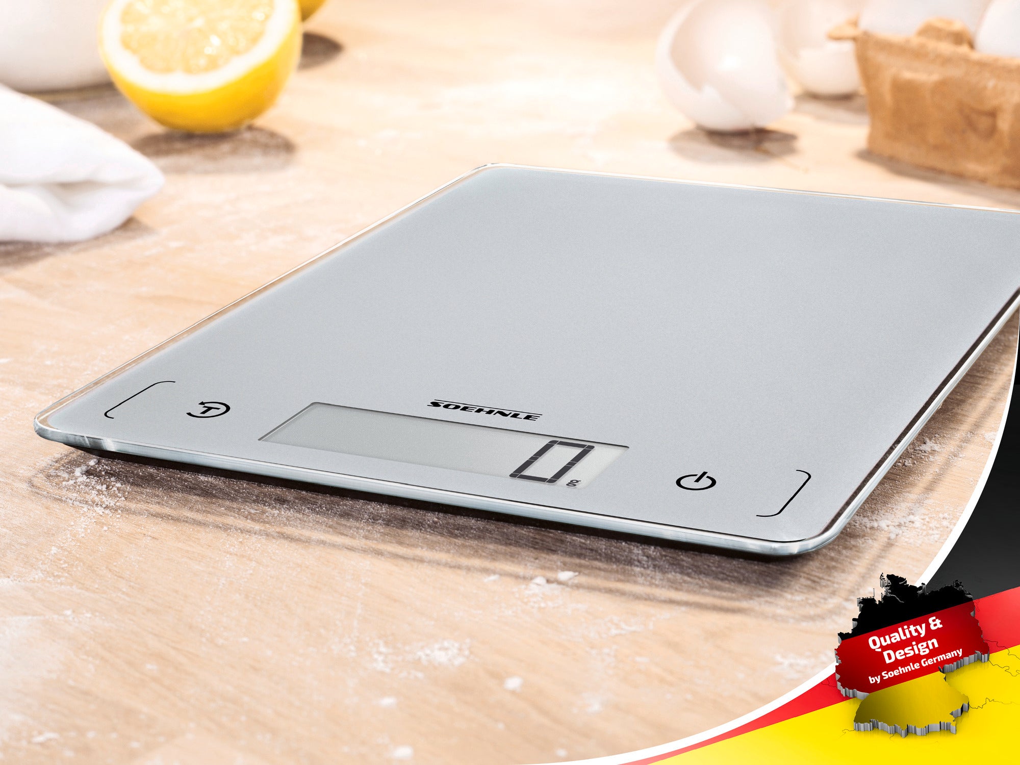 Digital kitchen scales by Soehnle on a work surface with flour and lemons in the background. The scales have a modern design with a clear display. Ideal for precise weighing.