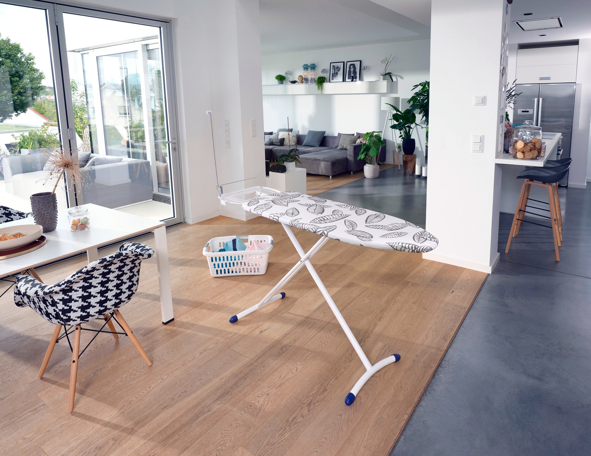 Bügelbrett Air Board Express L Solid MAXX in einem modernen Wohnzimmer. Das Brett steht auf einem Holzboden, umgeben von stilvollen Möbeln und Pflanzen, mit viel natürlichem Licht.