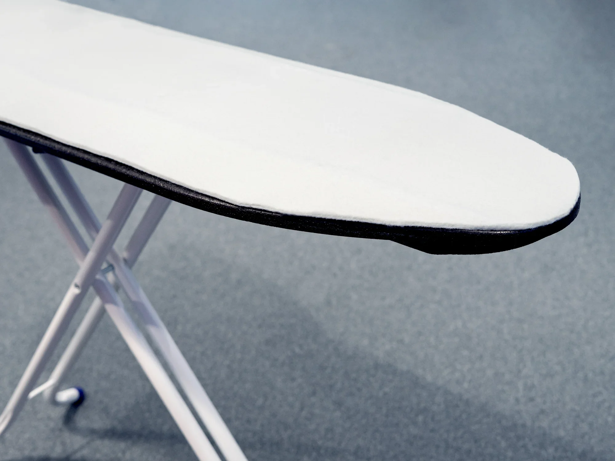 Relleno de una tabla de planchar sobre una tabla de planchar. El relleno es blanco y se adapta perfectamente a la forma de la tabla de planchar para garantizar un planchado perfecto.