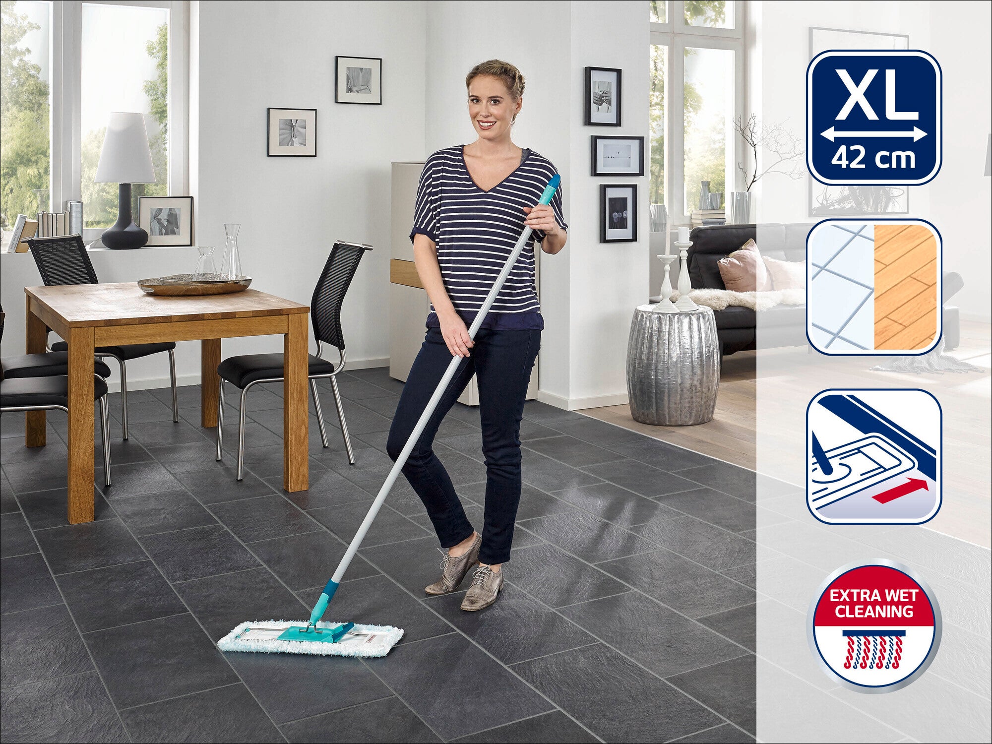 A woman cleans the floor with a Leifheit floor mop. The mop has an XL cleaning pad that is 42 cm wide. A dining area with a table and chairs can be seen in the background.