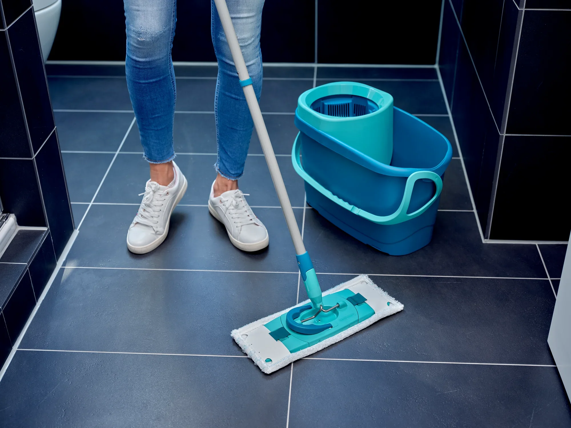 One person cleans a tiled floor with the CLEAN TWIST M micro duo replacement cover. The mop has a blue design and is used with a matching bucket. Ideal for thorough cleaning.