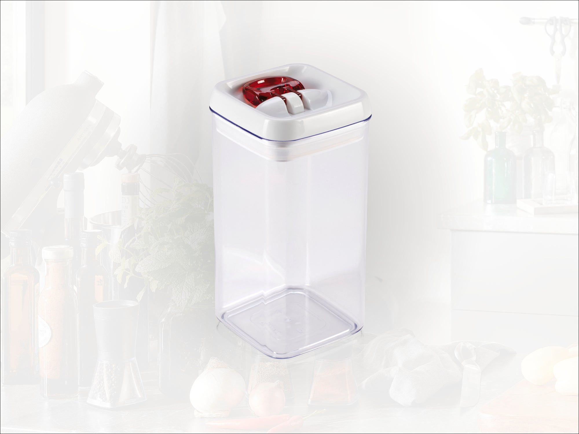 A transparent, rectangular storage container with a red lid. Ideal for storing food in the kitchen. Kitchen utensils are visible in the background.