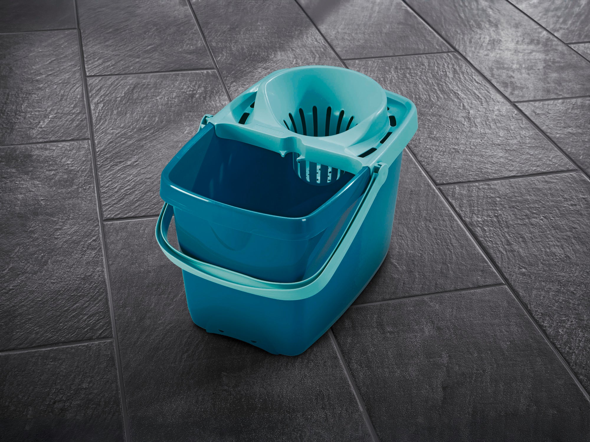 Un secchio Profi XL turchese con filtro integrato su un pavimento piastrellato scuro. Il secchio è robusto e ideale per pulire efficacemente i pavimenti.
