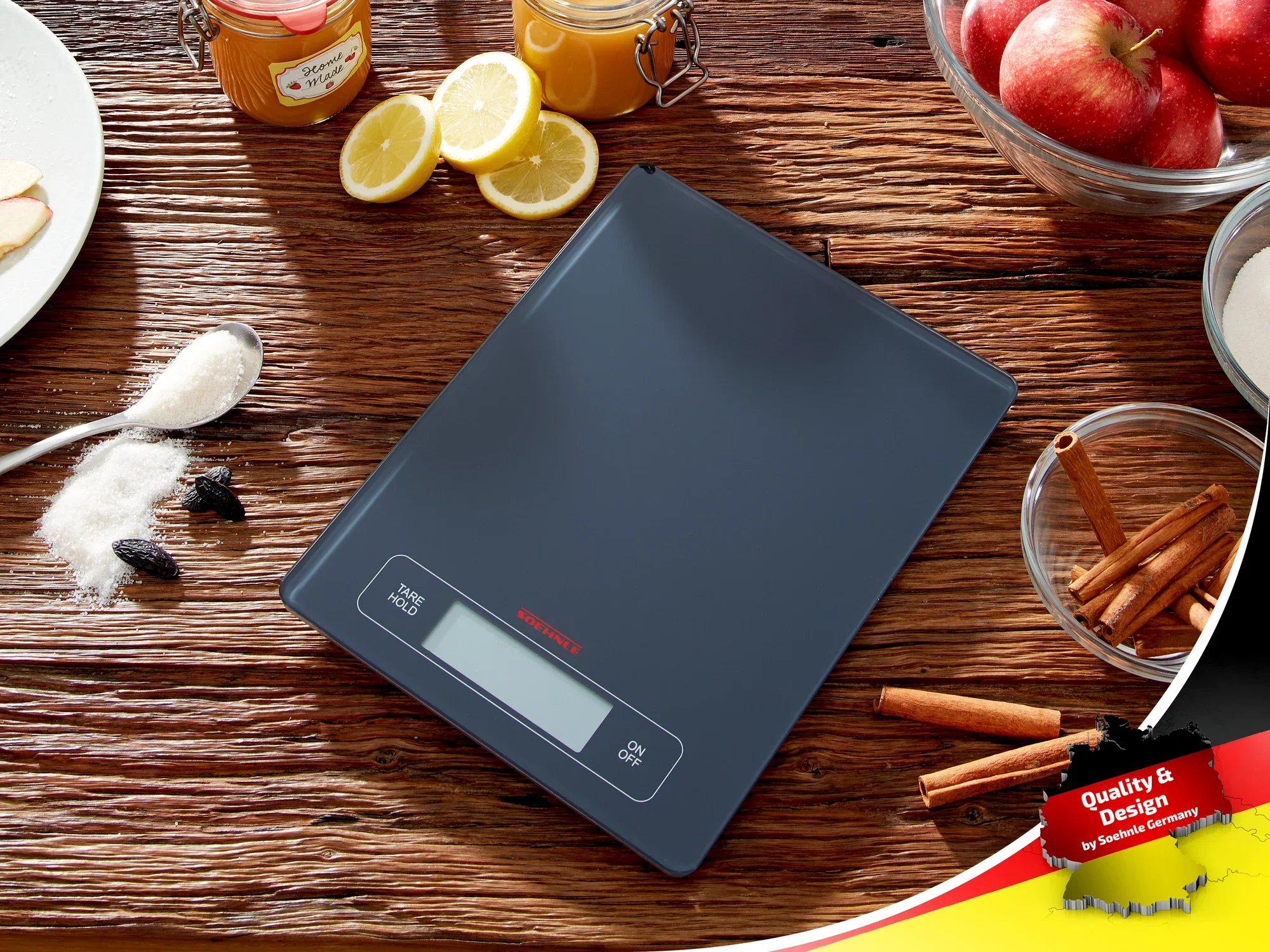 Digitale keukenweegschaal van Soehnle op een houten tafel, omringd door ingrediënten zoals kaneelstokjes, appels en citroenen. Ideaal voor nauwkeurig wegen bij het koken en bakken.