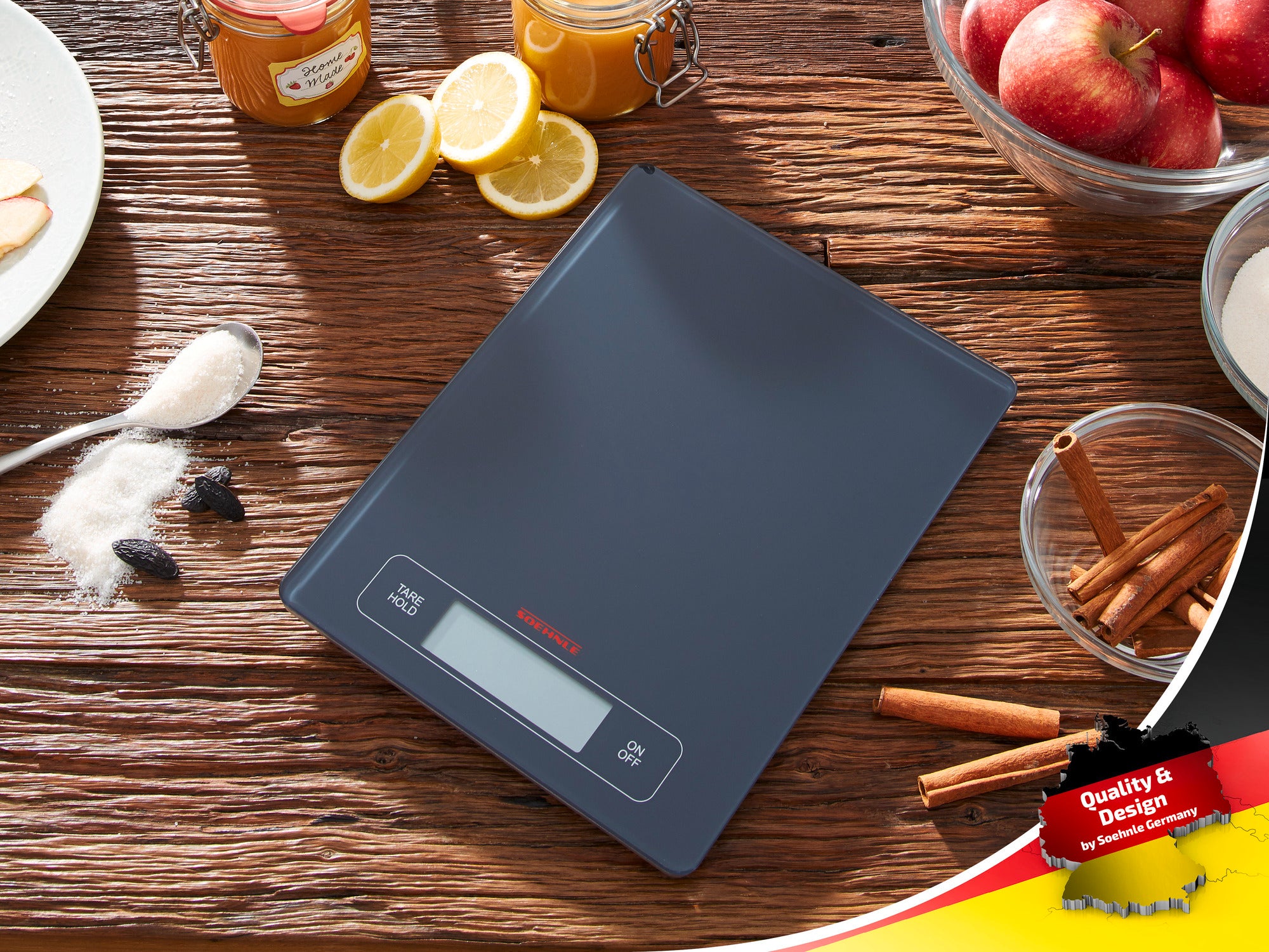 Digitale keukenweegschaal van Soehnle op een houten tafel, omringd door ingrediënten zoals kaneelstokjes, appels en citroenen. Ideaal voor nauwkeurig wegen bij het koken en bakken.