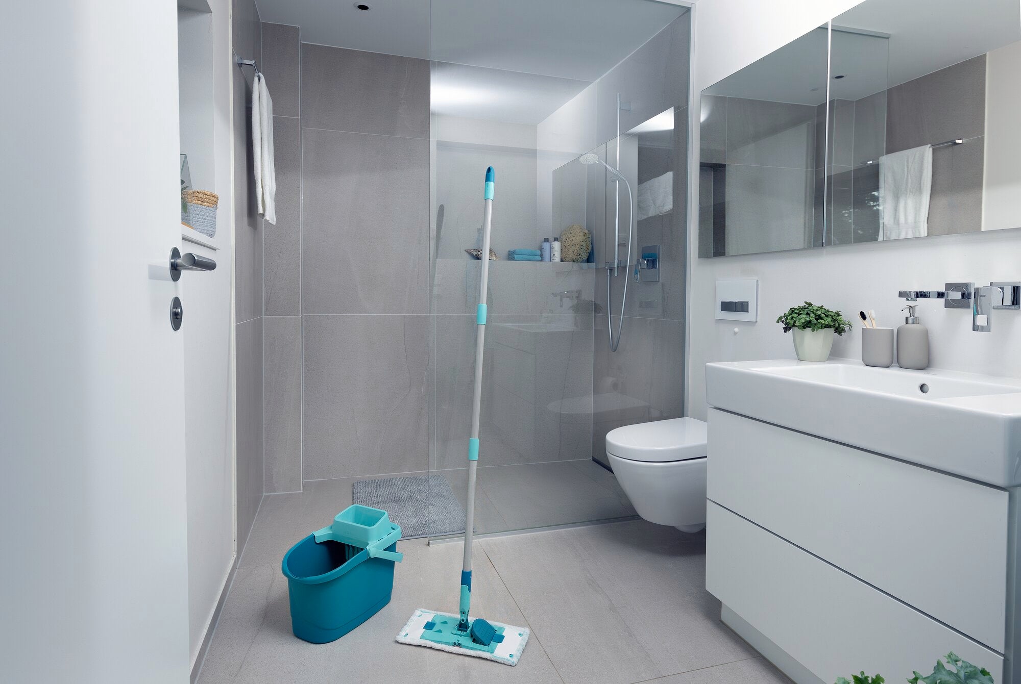 Ein modernes Badezimmer mit einem POWER CLEAN Set. Der Bodenwischer steht neben einem Eimer auf dem hellen Fliesenboden. Die Umgebung wirkt sauber und ordentlich, ideal für eine gründliche Reinigung.