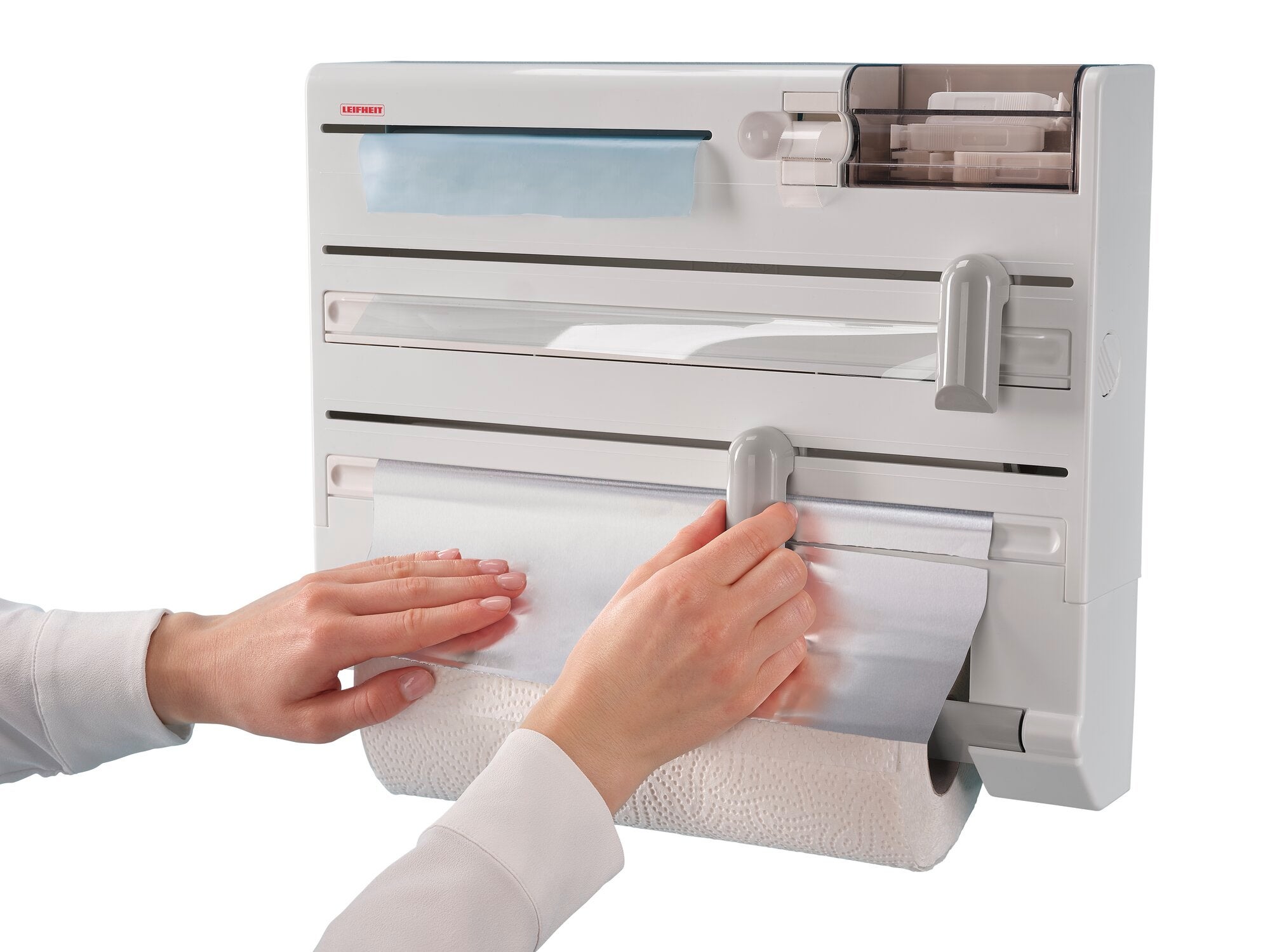 Wandrollenhalter Parat Plus: Eine Person zieht Alufolie aus einem modernen, an der Wand montierten Halter, der Platz für Folien, Papierrollen und mehr bietet.