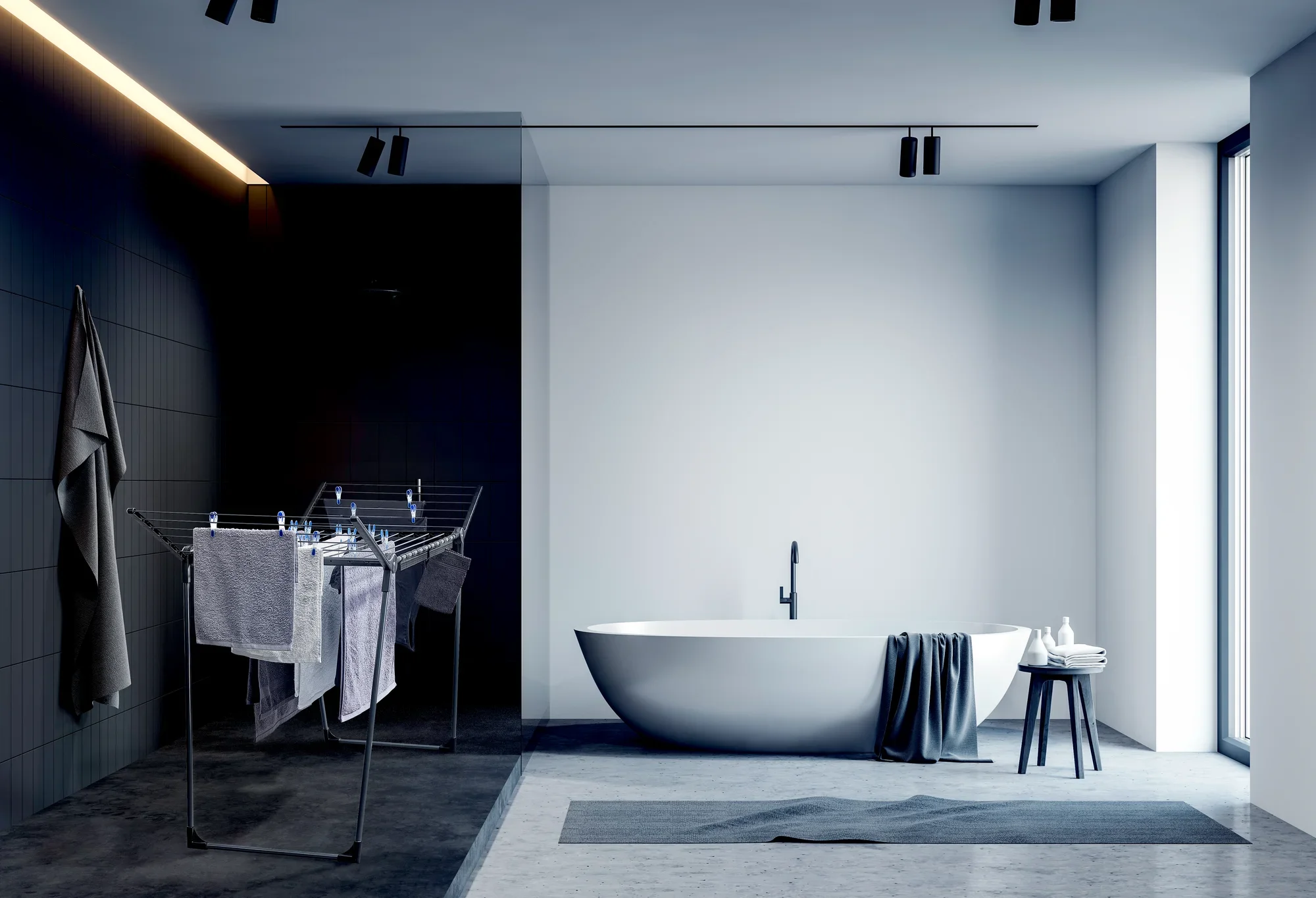 Wolnostojąca suszarka Pegasus 180 Solid w nowoczesnej łazience z ciemnymi kafelkami i wolnostojącą wanną. Suszarka jest załadowana ręcznikami i stoi obok wanny.