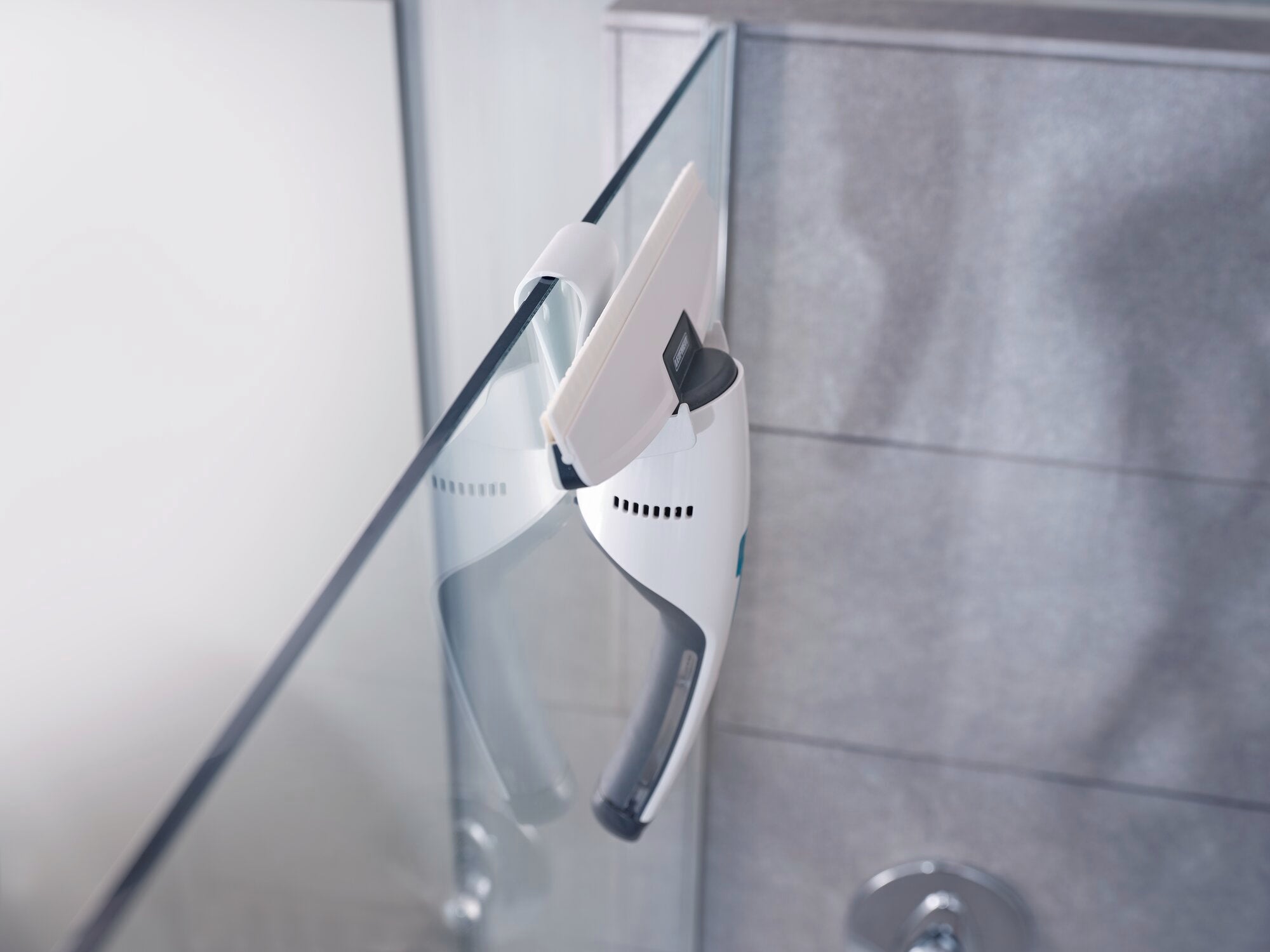 Nemo raamstofzuiger in gebruik op een glazen oppervlak. Het apparaat is ergonomisch ontworpen en zorgt voor een streeploze reiniging. Ideaal voor ramen en badkamers.
