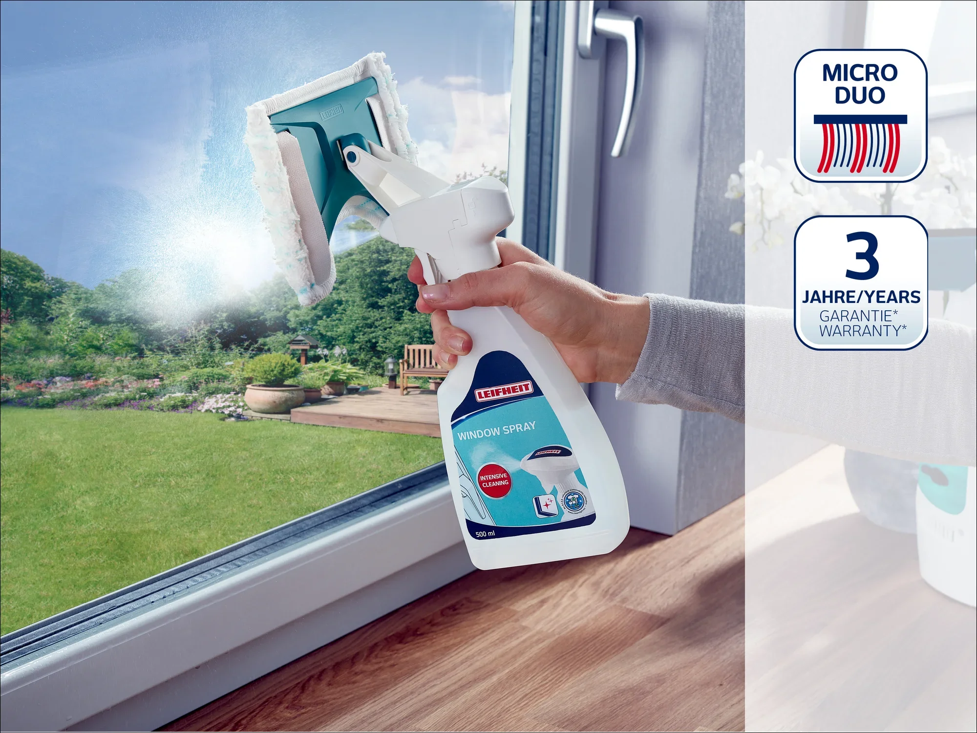 Osoba czyści duże okno za pomocą odkurzacza do okien Leifheit. W tle widać zadbany ogród. Produkt zapewnia czyszczenie bez smug.