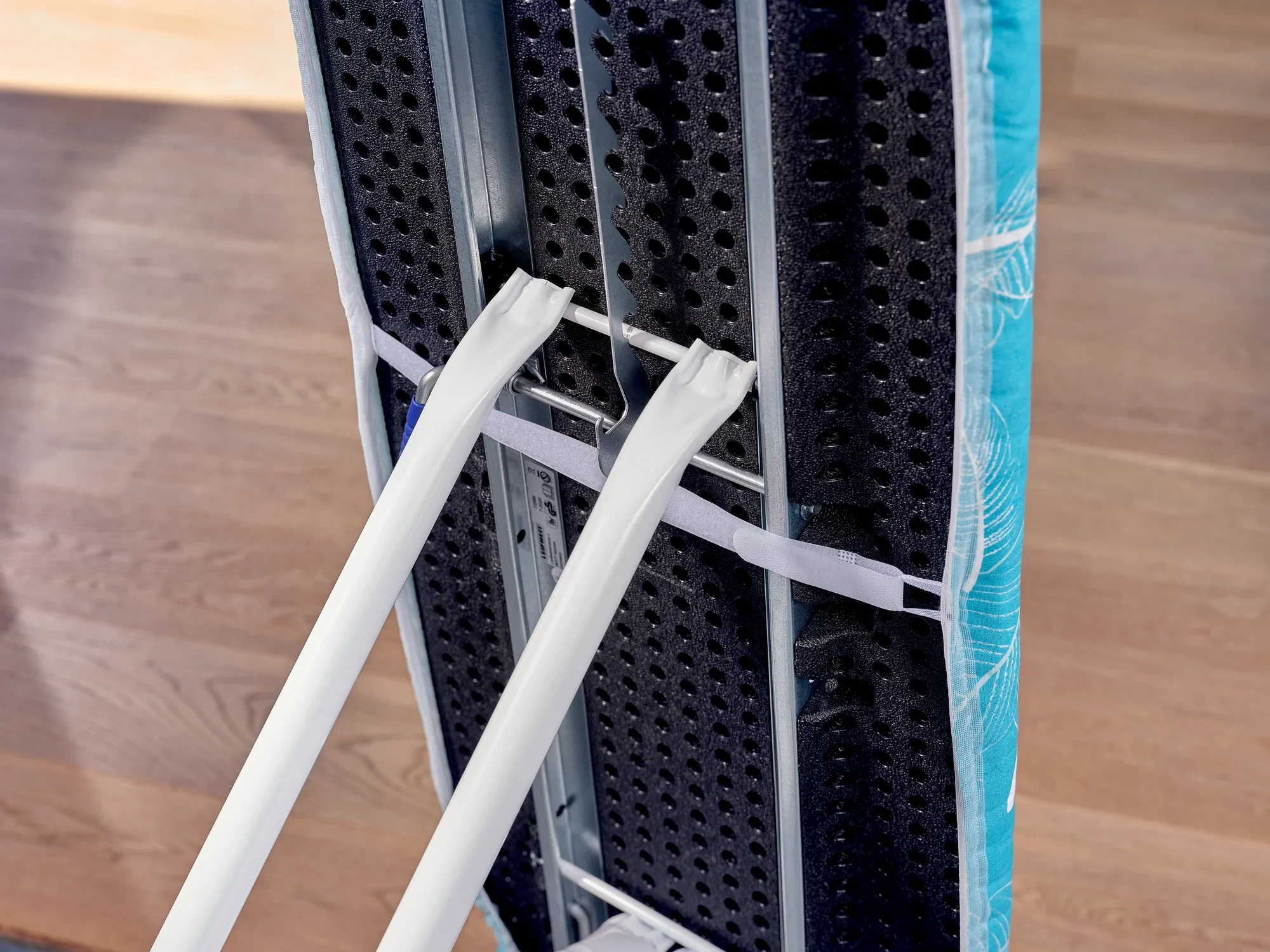 Bügelbrett mit dem Bezug "Thermo Reflect M" in Nahaufnahme. Der Bezug zeigt eine reflektierende Oberfläche, die das Bügeln effizienter macht, auf einem Holzboden.