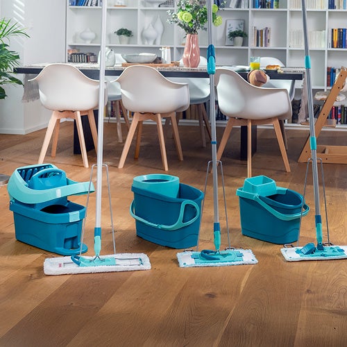Tuerkisfarbene Wischmops und Eimer auf Holzfussboden, links ein Sofa