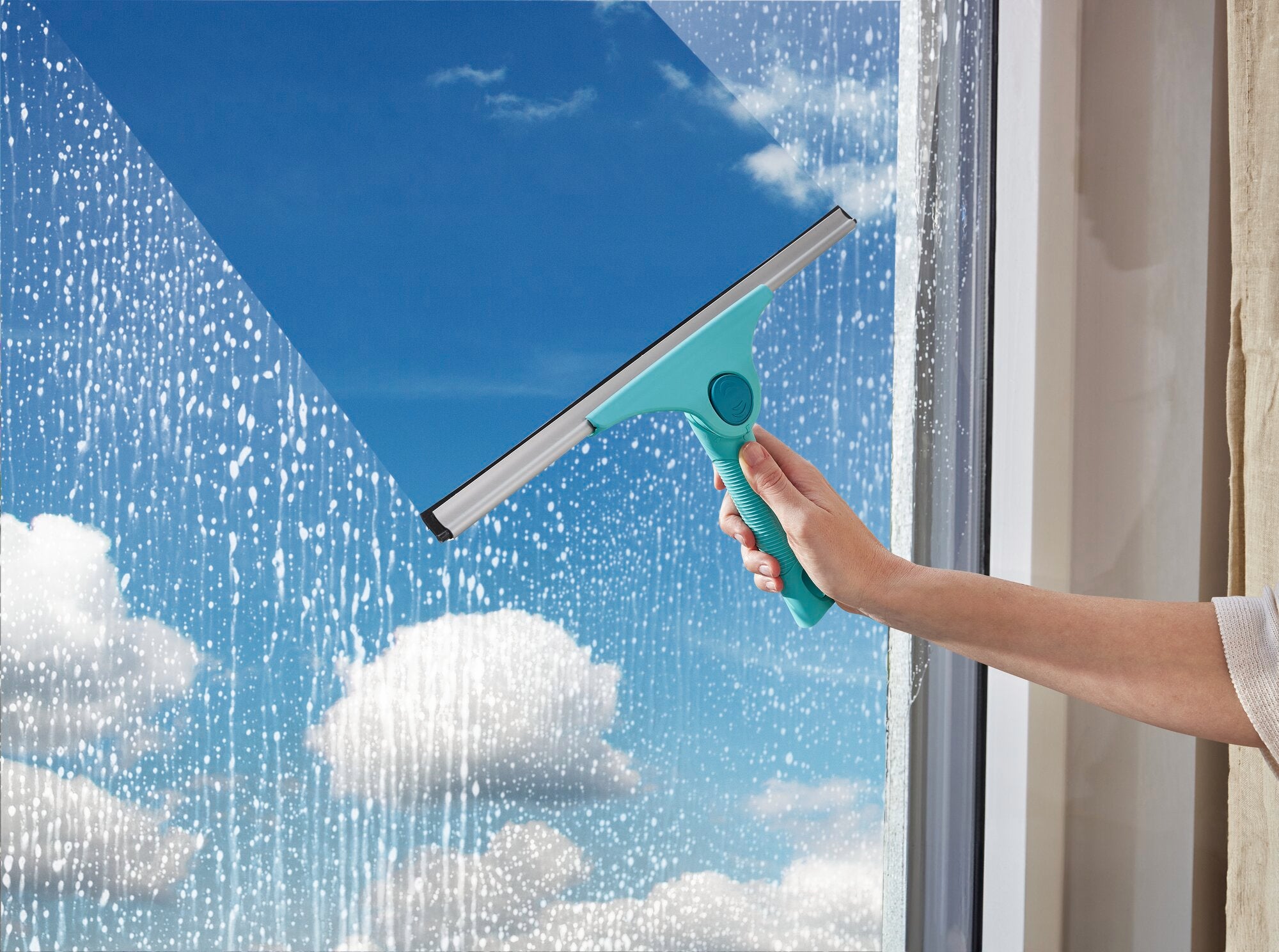 Ein Fensterreiniger, der als Window Slider 2in1 XL ProReach bekannt ist, wird verwendet, um ein großes Fenster zu reinigen. Der Himmel ist klar und sonnig.