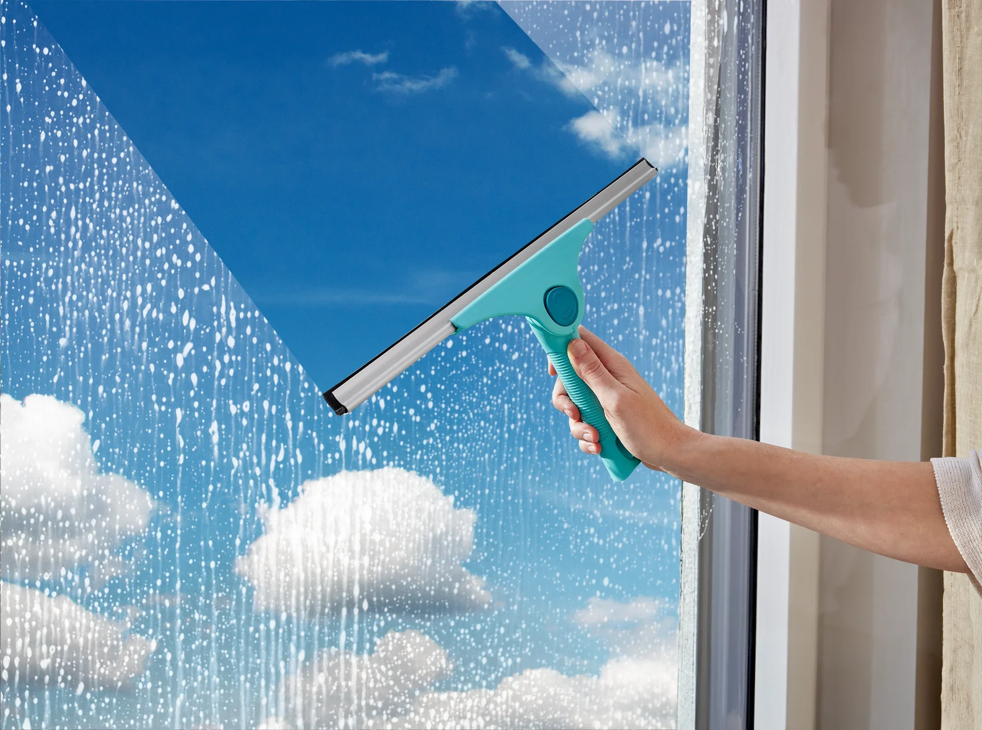 A window cleaner known as Window Slider 2in1 XL ProReach is being used to clean a large window. The sky is clear and sunny.