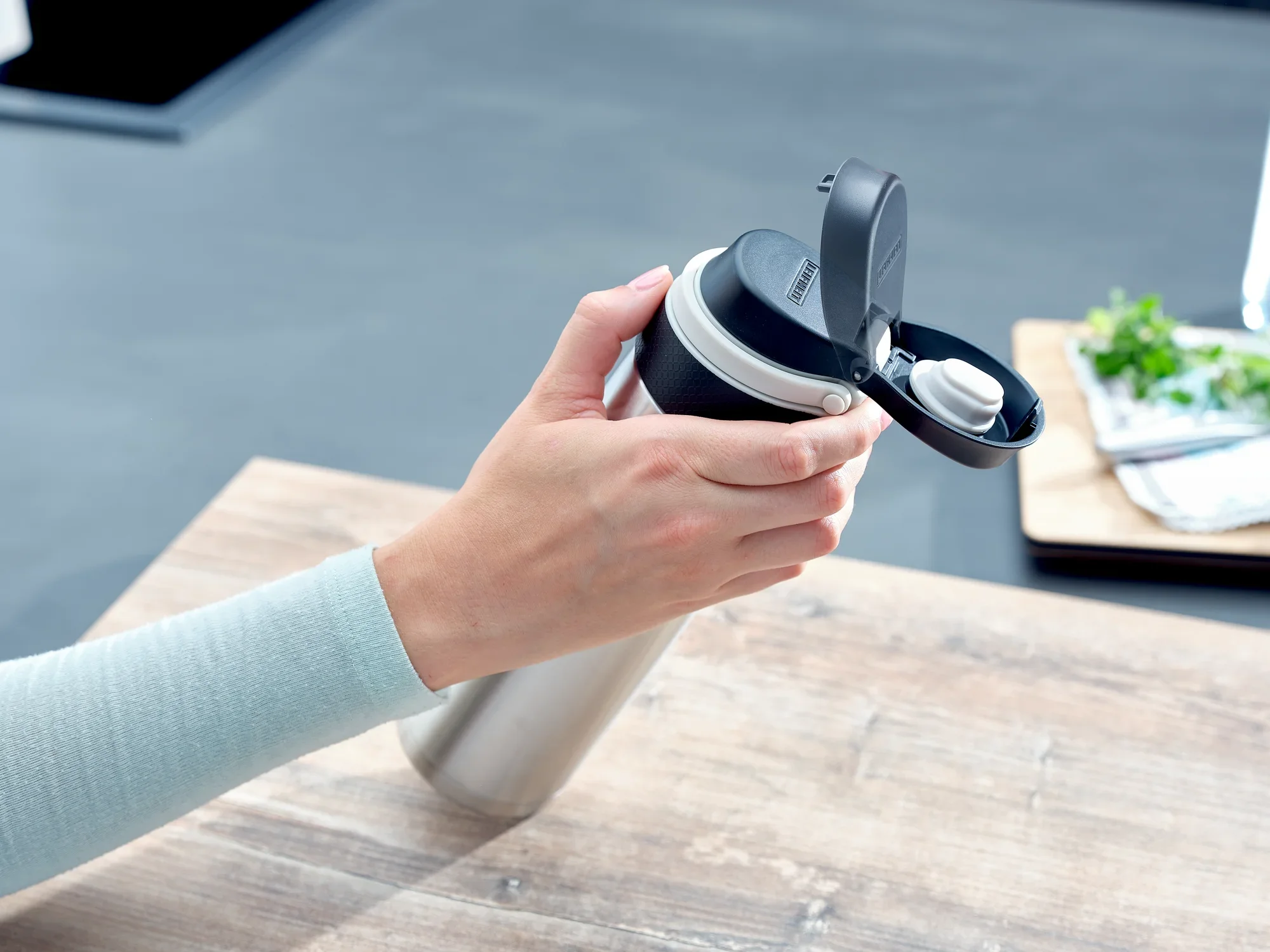 Izolowany kubek Flip 600ml w kolorze srebrnym jest trzymany jedną ręką. Kubek ma praktyczną pokrywkę typu flip-top, idealną w podróży. Idealny do gorących i zimnych napojów.