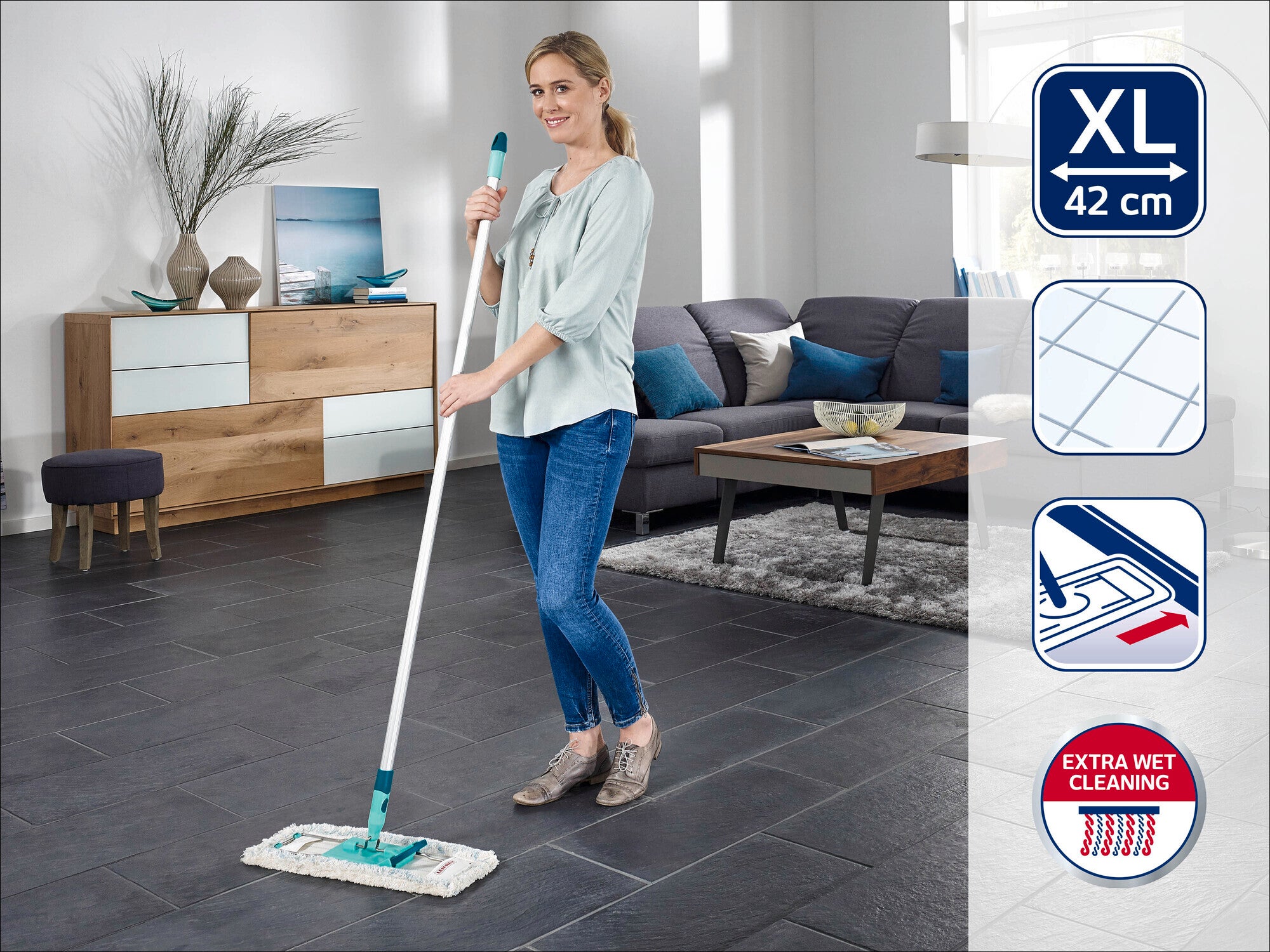 Une femme nettoie le sol avec un balai Leifheit XL 42 cm dans un salon moderne. Le balai est idéal pour le nettoyage très humide et les grandes surfaces.