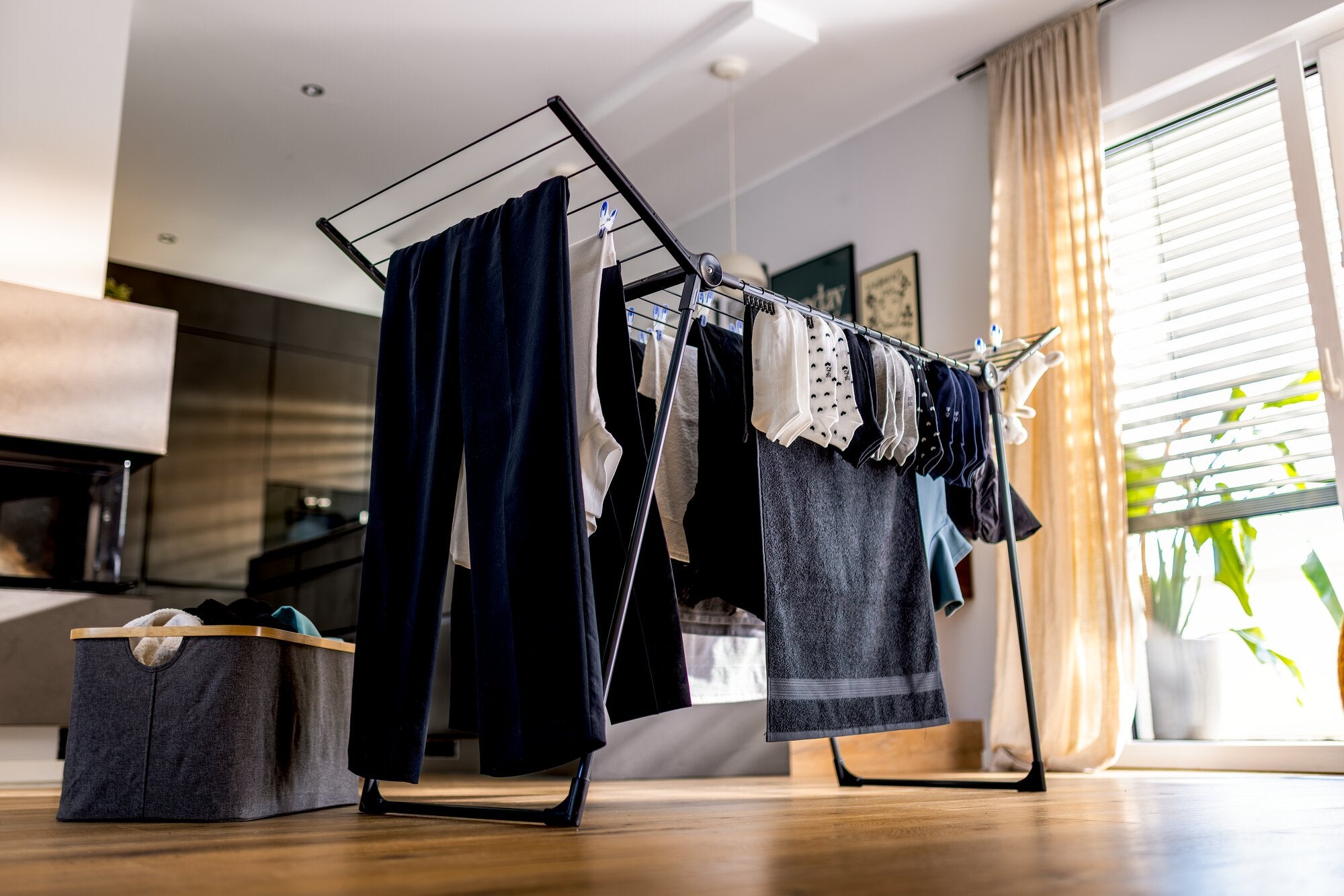 Séchoir à linge Leifheit Pegasus Family 18 m en noir, installé dans une chambre lumineuse, avec des vêtements et des serviettes en train de sécher sur des ailes dépliantes et des supports latéraux, montrant une grande capacité de séchage du linge en intér