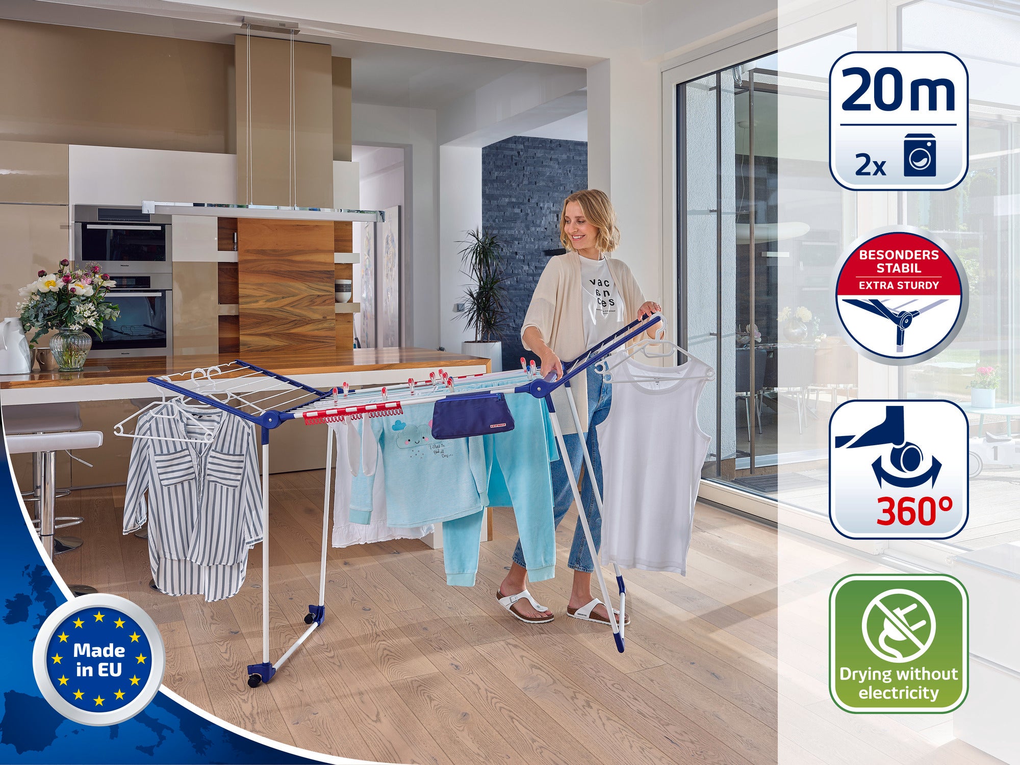 Een vrouw staat in een moderne woonkamer en gebruikt een vrijstaande wasdroger om kleding te drogen. De droger heeft een drooglengte van 20 meter en is bijzonder stabiel. Ideaal voor milieuvriendelijk drogen zonder elektriciteit.