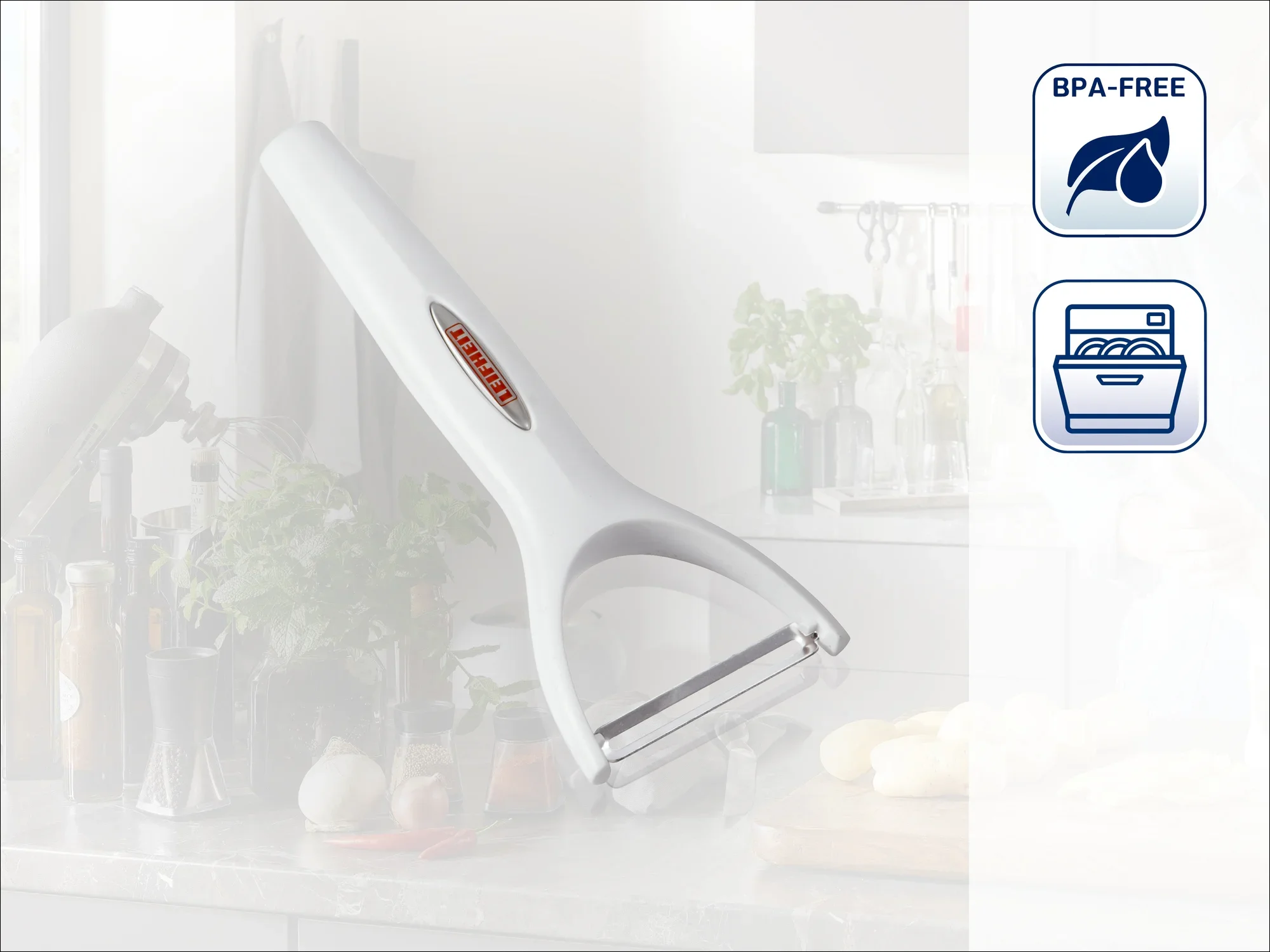 Biała obieraczka leży na blacie kuchennym. W tle widoczne są przybory kuchenne i świeże składniki. Produkt nie zawiera BPA i nadaje się do mycia w zmywarce.