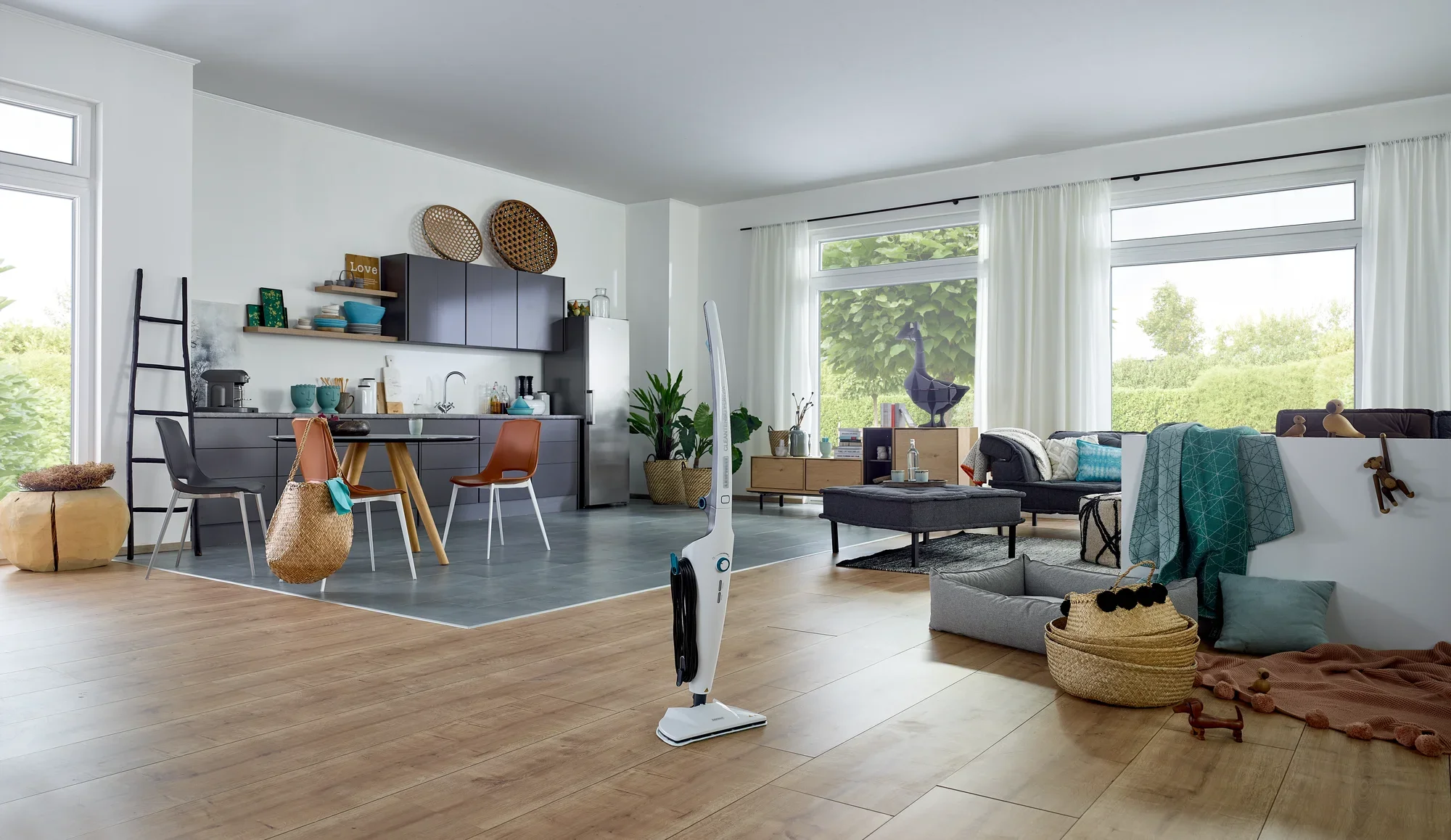 Nettoyeur vapeur CleanTenso Power dans un salon moderne avec parquet. À l'arrière-plan, on aperçoit une cuisine ouverte avec une table et des chaises.
