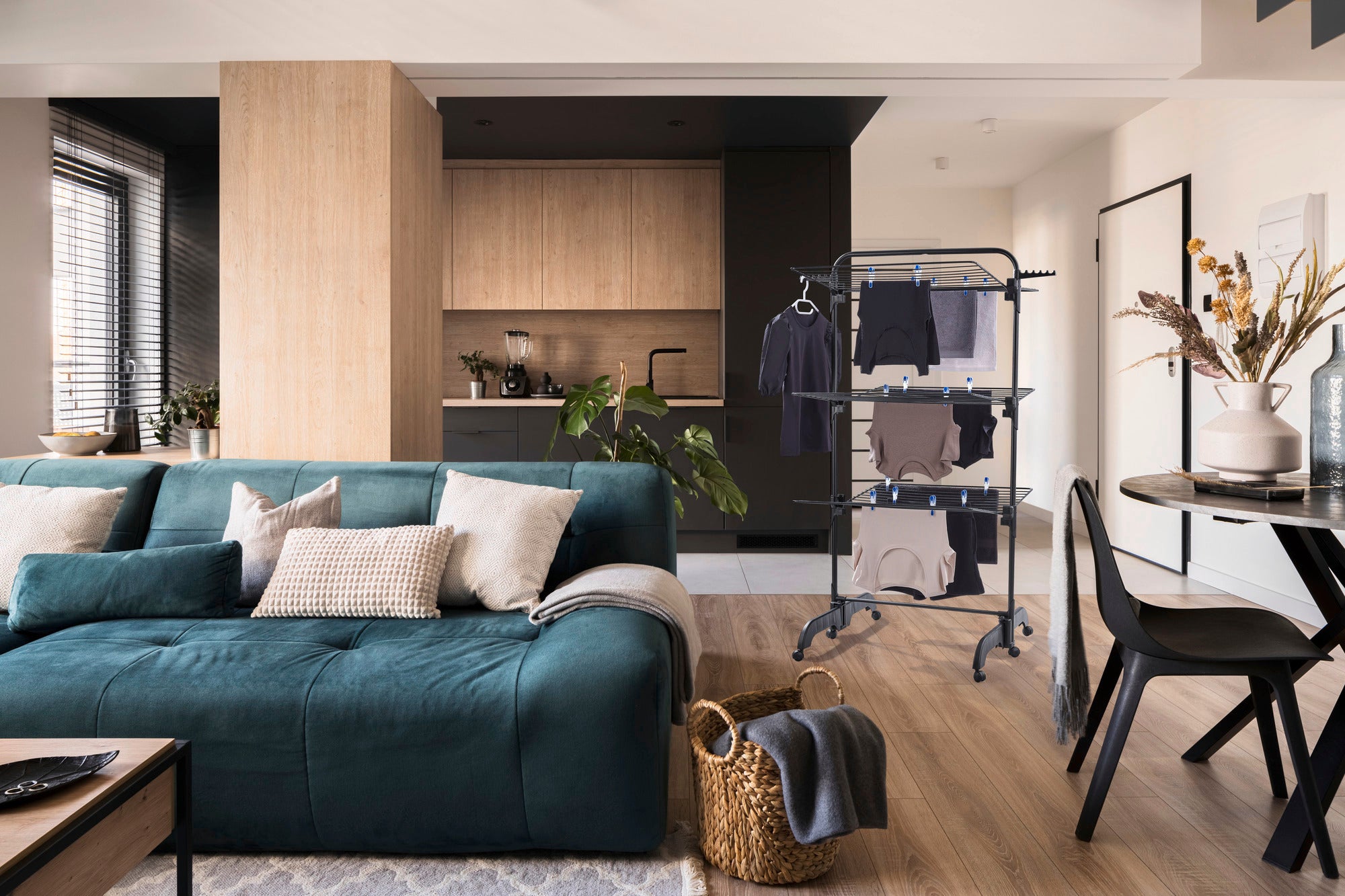 Comfort Tower 420 tower dryer in a modern living room. The black dryer stands next to a green sofa and a dining table, surrounded by stylish furnishings.