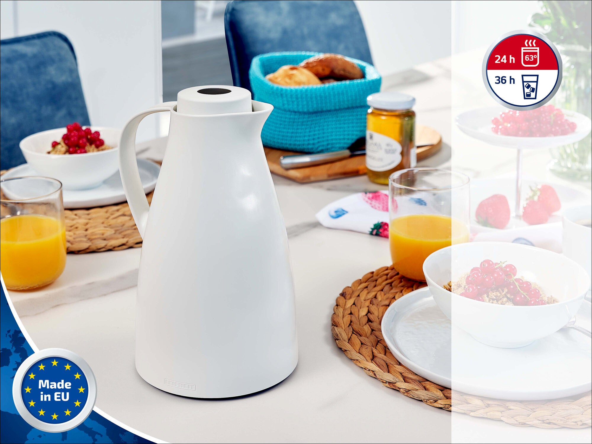 Leifheit Isolierkanne Harmonic in Weiß auf gedecktem Frühstückstisch mit Orangensaft, Beeren, Gebäck und Marmelade; dekorativ inszeniert, mit Hinweisen auf 24 Stunden heiß, 36 Stunden kalt und Made in EU.