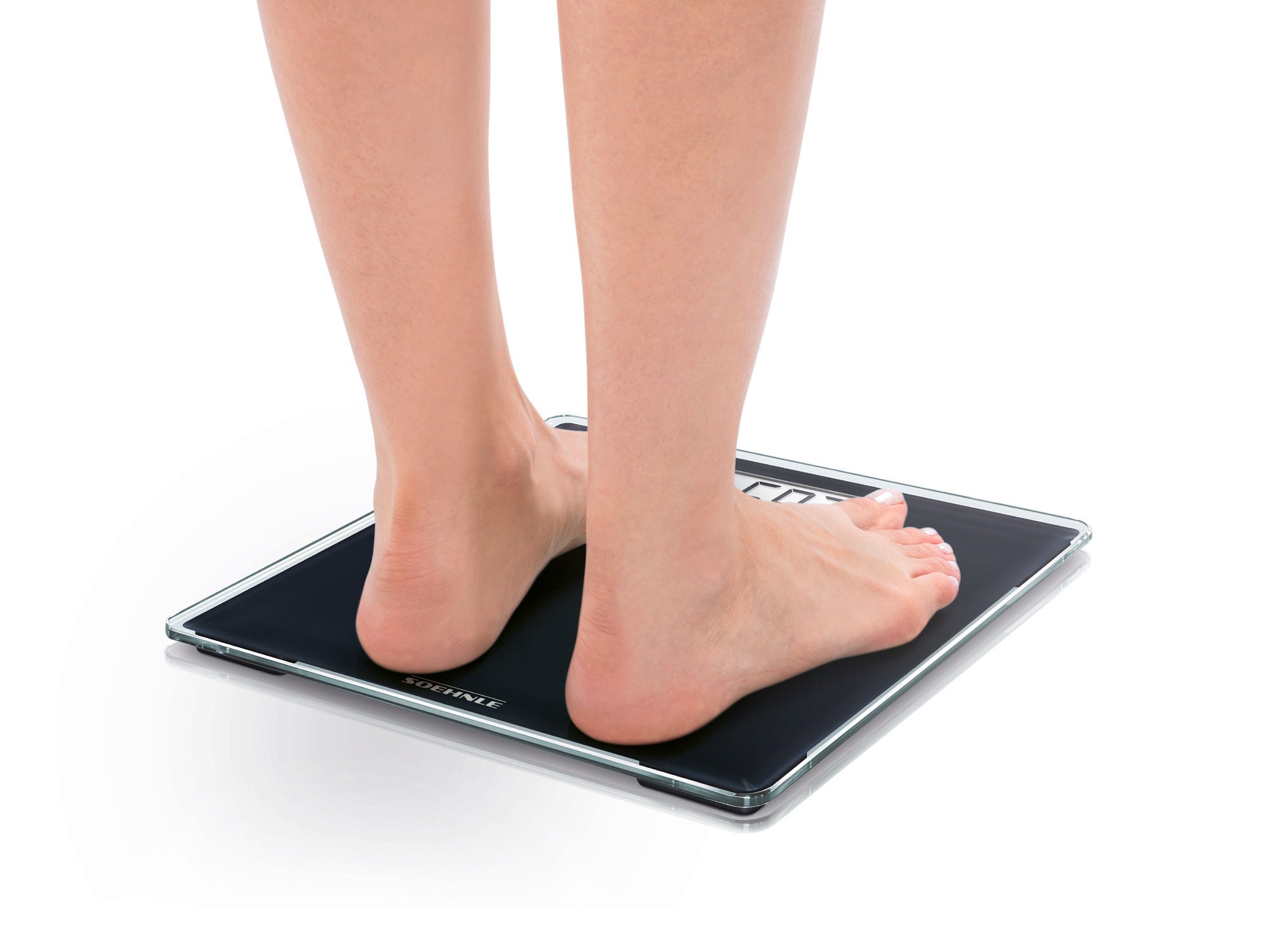 Eine Person steht barfuß auf einer digitalen Personenwaage, Modell Style Sense Compact 100. Die Waage hat ein schlankes, modernes Design und zeigt das Gewicht präzise an.