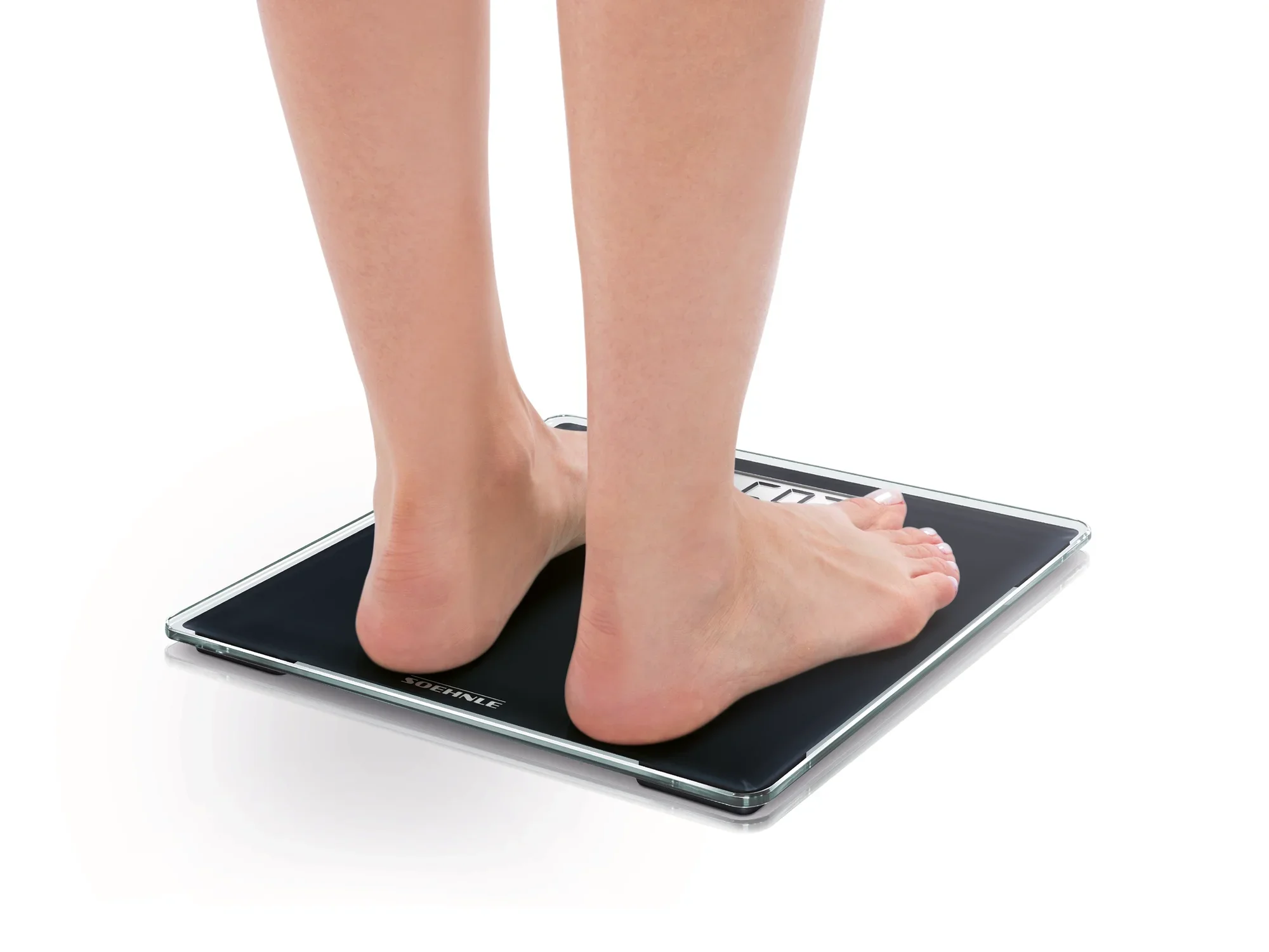 Eine Person steht barfuß auf einer digitalen Personenwaage, Modell Style Sense Compact 100. Die Waage hat ein schlankes, modernes Design und zeigt das Gewicht präzise an.