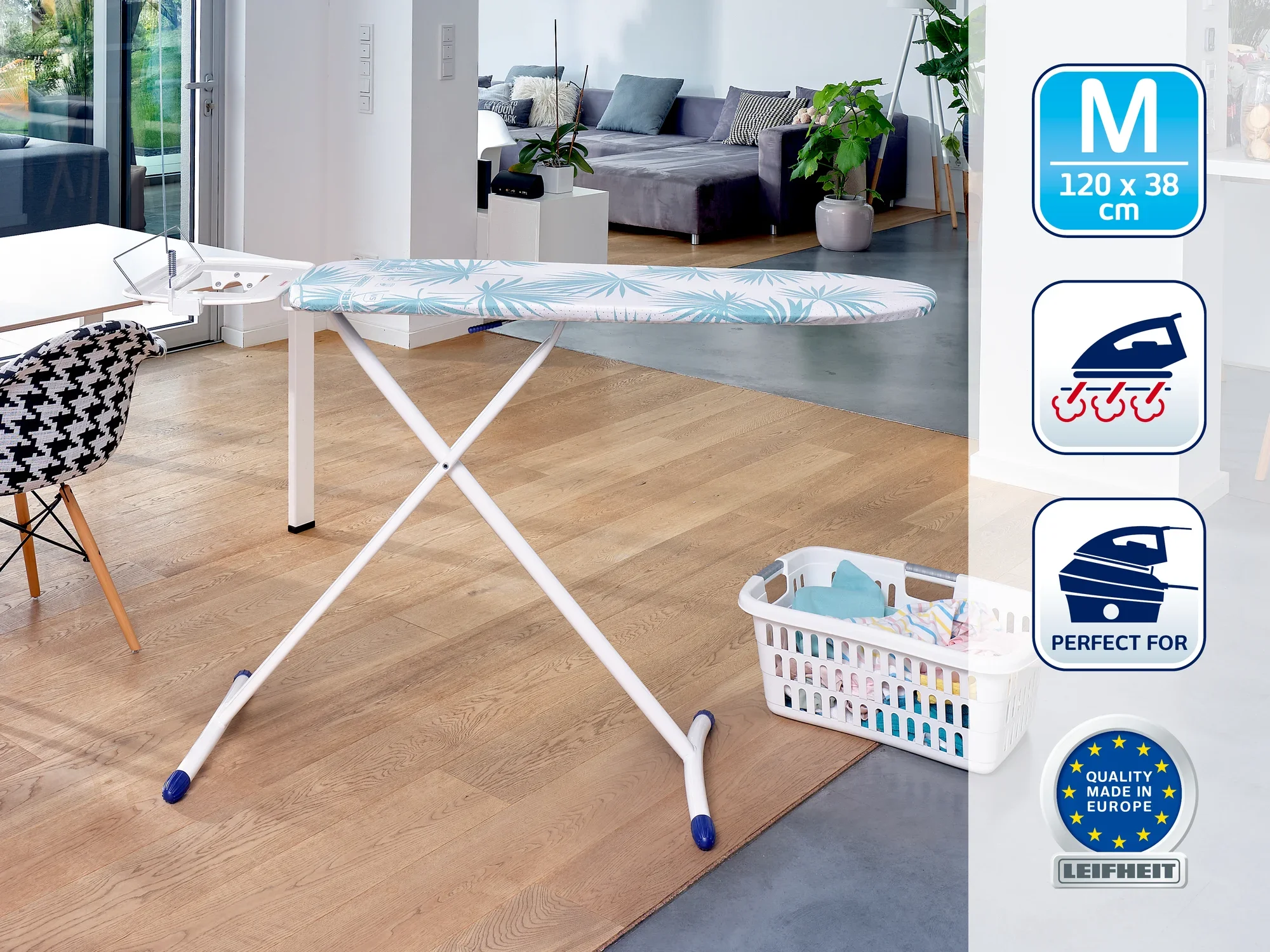 Table à repasser moderne dans un salon lumineux. La table a une surface bleue à motifs et se trouve à côté d'un panier à linge. Idéale pour un repassage efficace.
