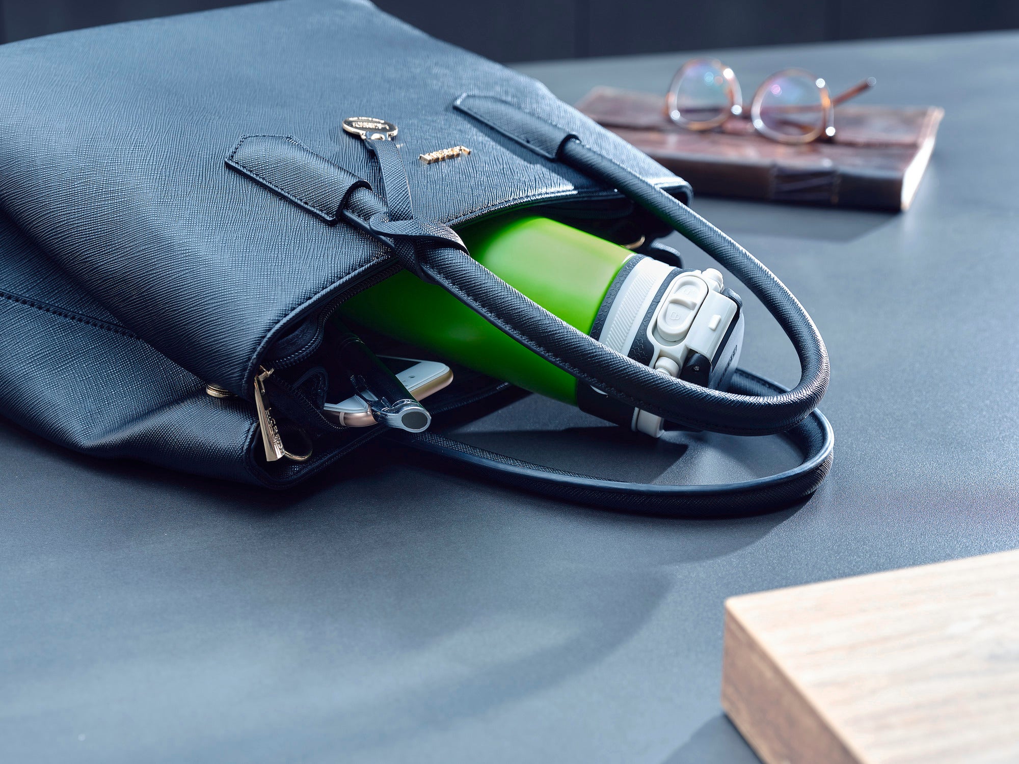 Un mug isotherme Flip vert d'une contenance de 350 ml dépasse d'un sac noir. Le mug est idéal pour les déplacements et garde les boissons chaudes ou froides.