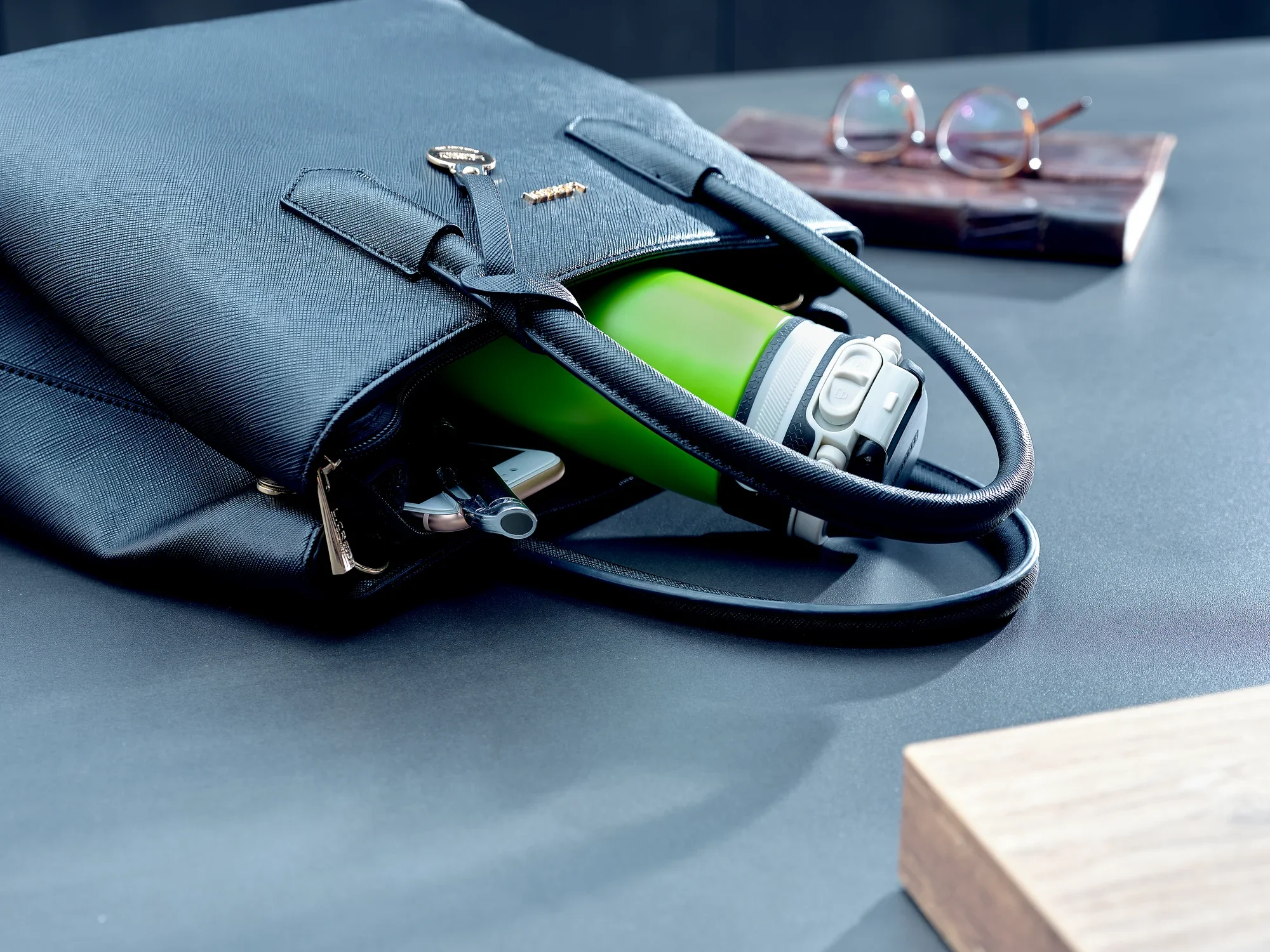 Zielony izolowany kubek Flip o pojemności 350 ml wystaje z czarnej torby. Kubek jest idealny do podróżowania i przechowywania gorących lub zimnych napojów.