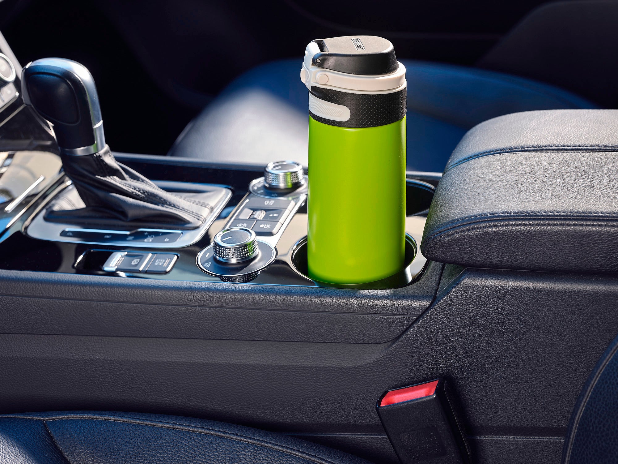 Isolierbecher Flip 600ml in Kiwi-Grün, platziert in einem Autohalter. Der Becher hat einen praktischen Klappdeckel und passt perfekt in den Getränkehalter eines Fahrzeugs.