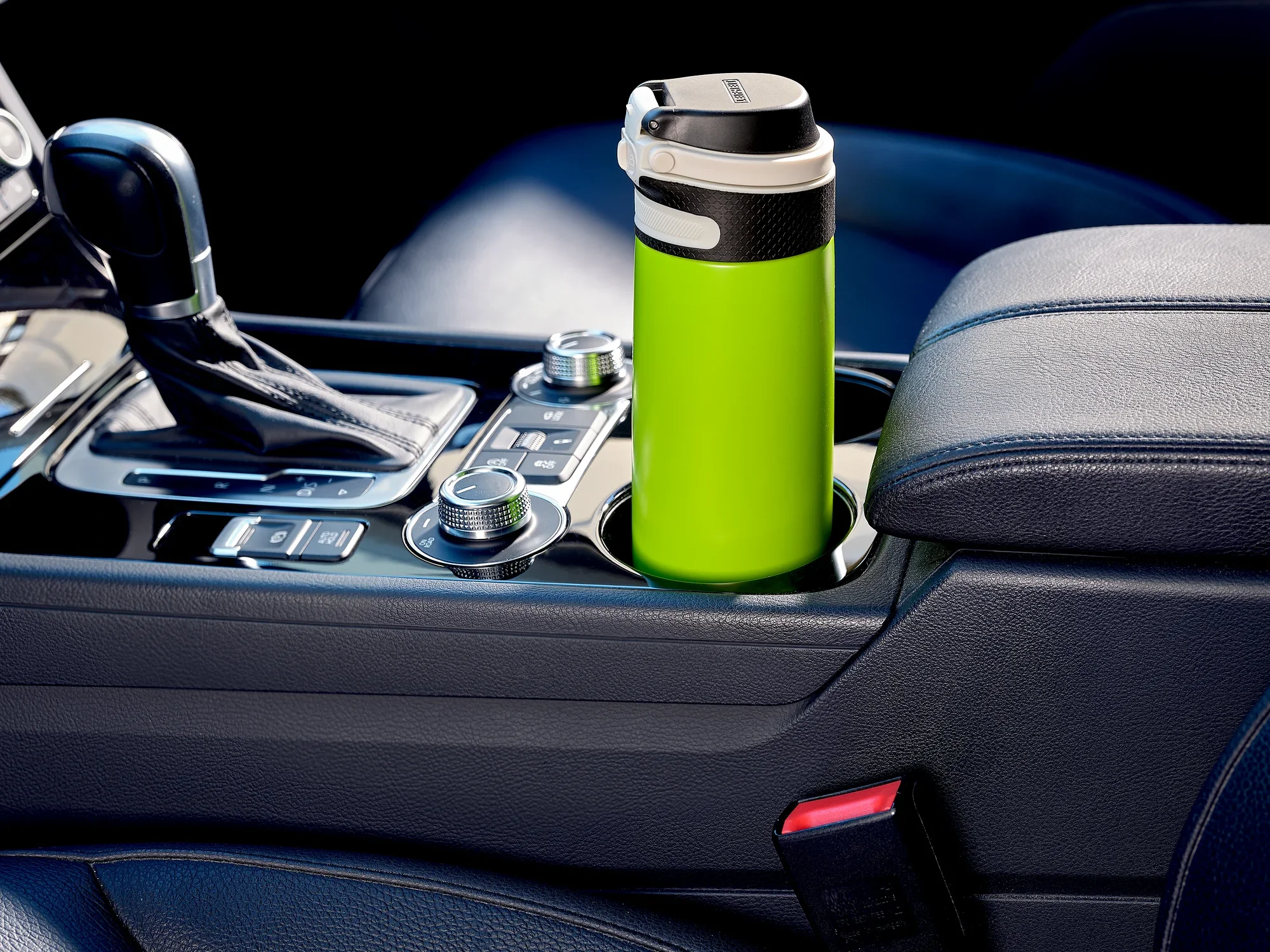 Kubek próżniowy Flip 600 ml w kolorze kiwi, umieszczony w uchwycie samochodowym. Kubek ma praktyczną pokrywkę typu flip-top i idealnie pasuje do uchwytu na kubek w samochodzie.