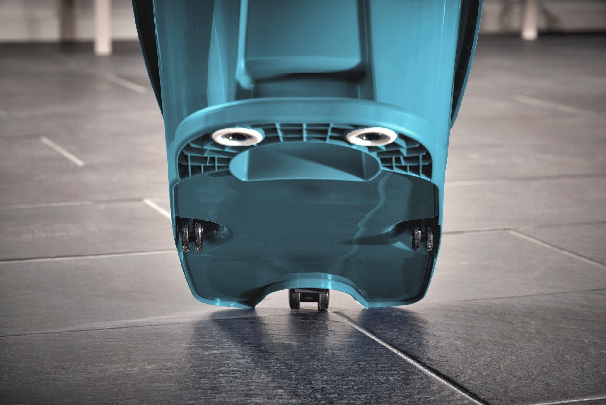 Een blauwe Profi XL moppers op een donkere tegelvloer. Het apparaat demonstreert zijn robuuste constructie en functionaliteit, ideaal voor het efficiënt schoonmaken van grote oppervlakken.