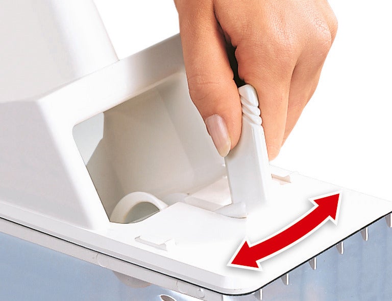 Una mano acciona la palanca de un deshuesador de ciruelas. La palanca es blanca y se mueve hacia la izquierda y hacia la derecha para activar la función de deshuesado.