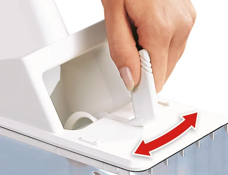 Jedna ręka obsługuje dźwignię drylownicy do śliwek. Dźwignia jest biała i przesuwa się ją w lewo i w prawo, aby aktywować funkcję drylowania.