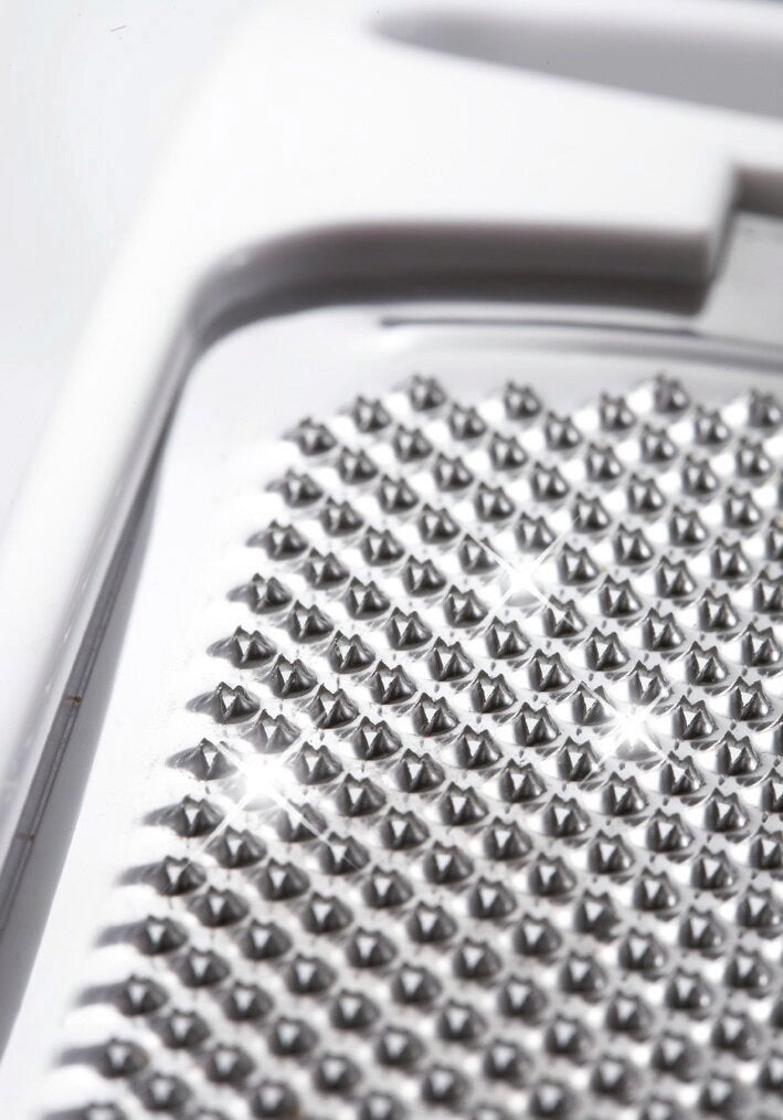 Nutmeg grater close-up. The sharp silver blades are clearly visible and reflect the light. Ideal for grating nutmeg in the kitchen.