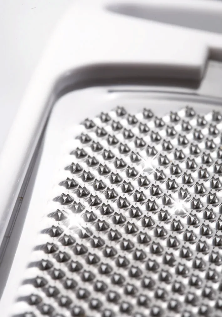 Râpe à muscade en gros plan. Les lames argentées et tranchantes sont clairement visibles et reflètent la lumière. Idéale pour râper des noix de muscade dans la cuisine.