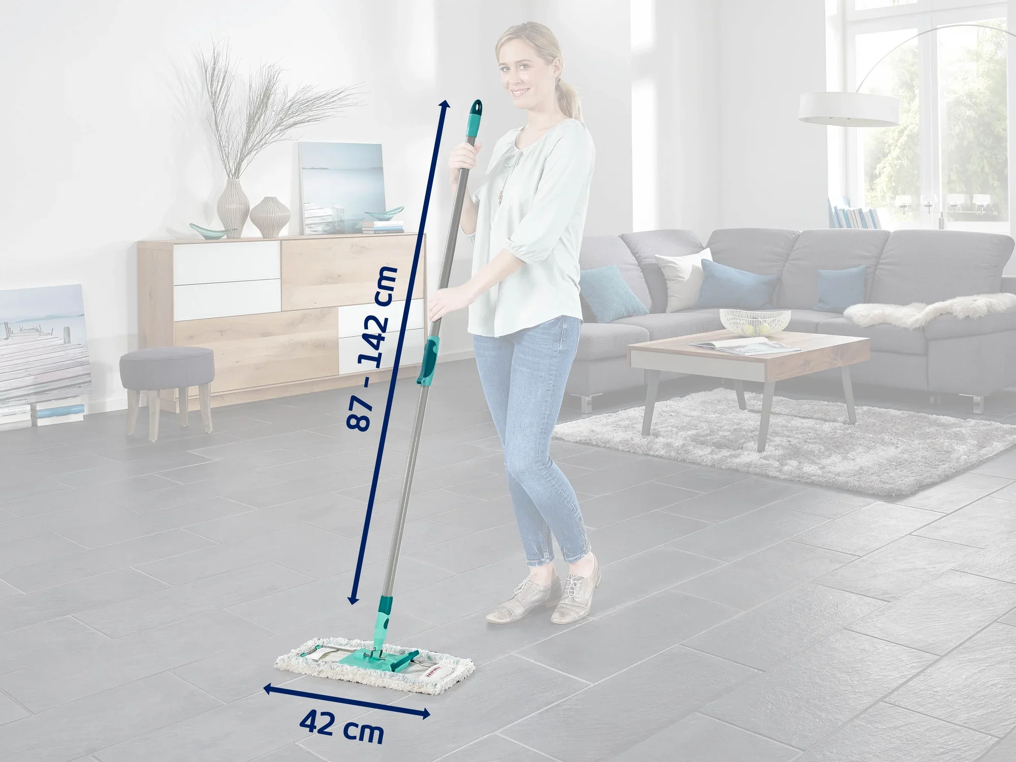 Eine Frau wischt den Boden in einem modernen Wohnzimmer mit einem Leifheit Bodenwischer. Der Wischer hat eine verstellbare Stange von 87 bis 142 cm und ein 42 cm breites Wischpad.
