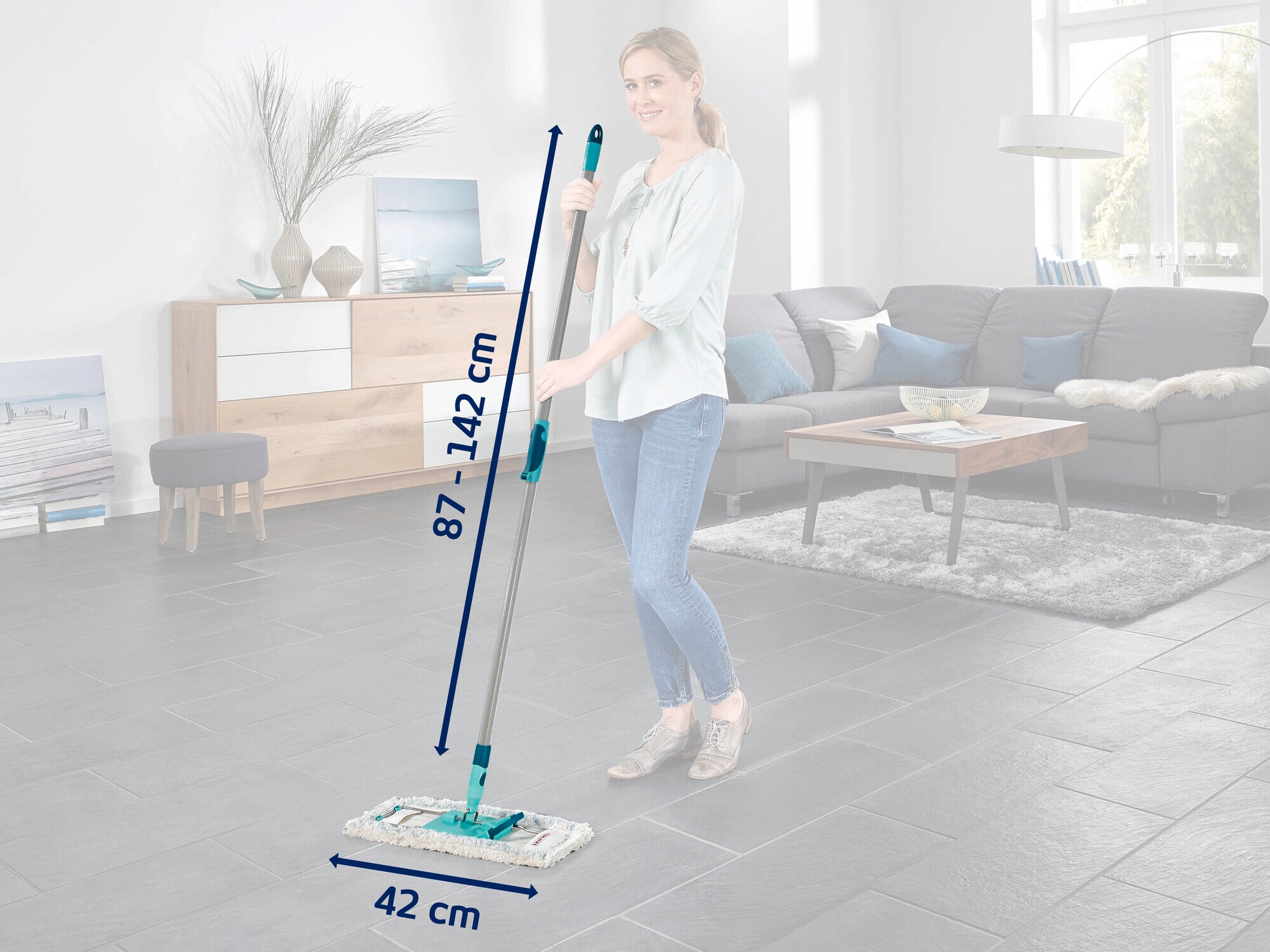 Eine Frau wischt den Boden in einem modernen Wohnzimmer mit einem Leifheit Bodenwischer. Der Wischer hat eine verstellbare Stange von 87 bis 142 cm und ein 42 cm breites Wischpad.