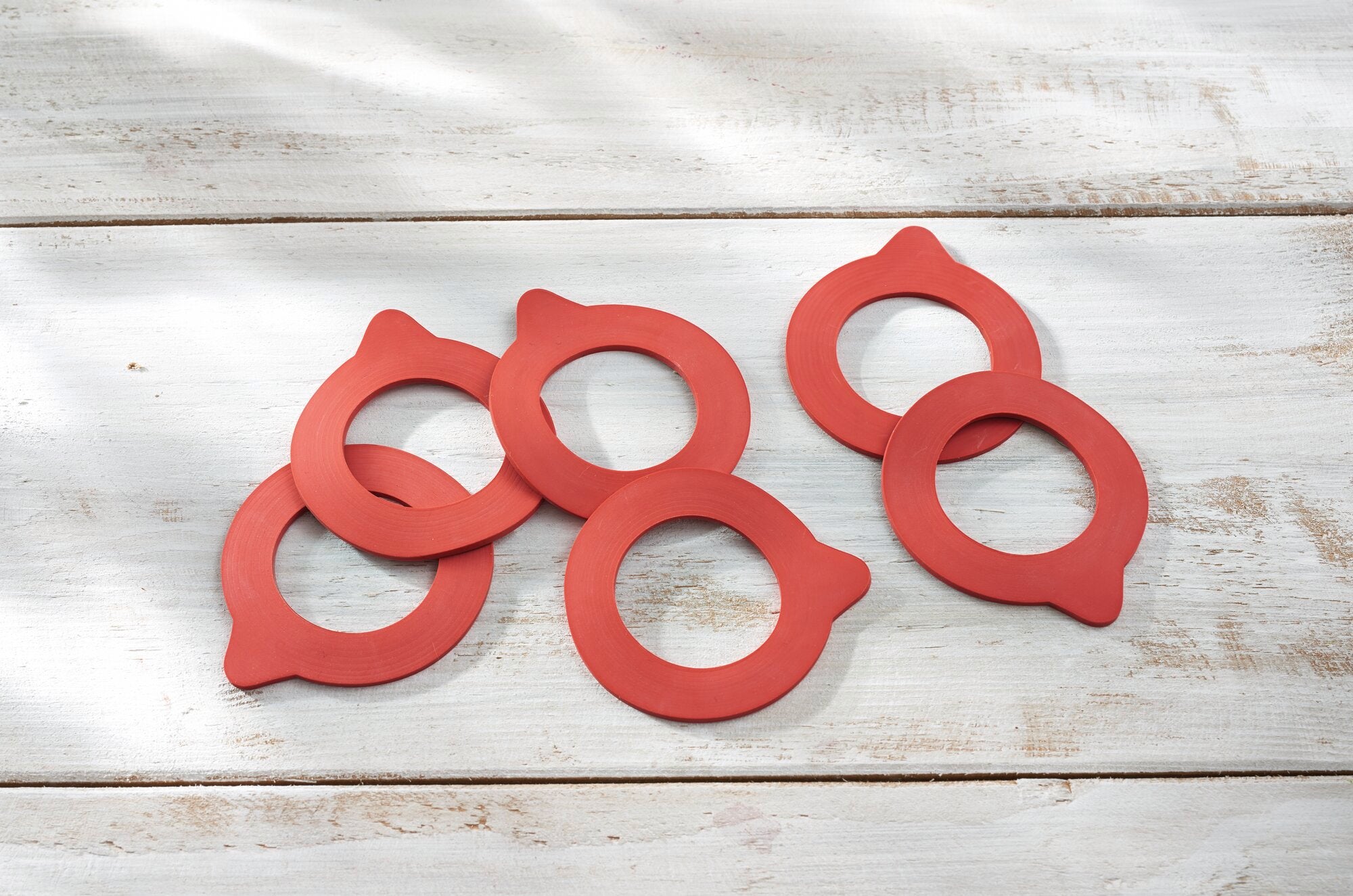 Ersatzgummiringe in Rot, 43x71 mm, auf einem hellen Holztisch arrangiert. Die Ringe sind gleichmäßig verteilt und bieten eine klare Ansicht ihrer Form und Farbe.