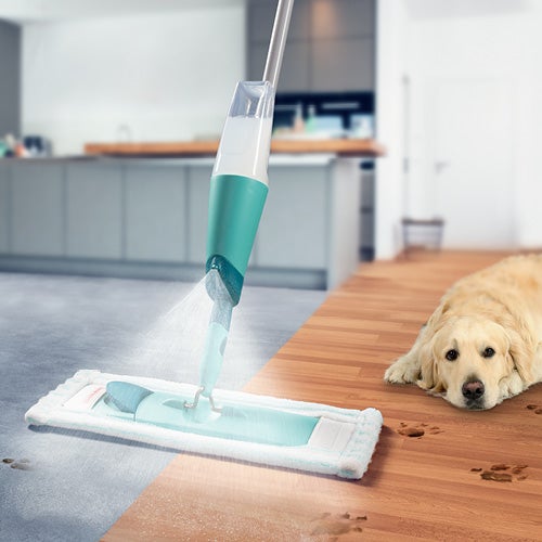 Een mop met waterreservoir reinigt een vloer; links tegels, rechts hout met hondentraps; een hond ligt op de achtergrond.