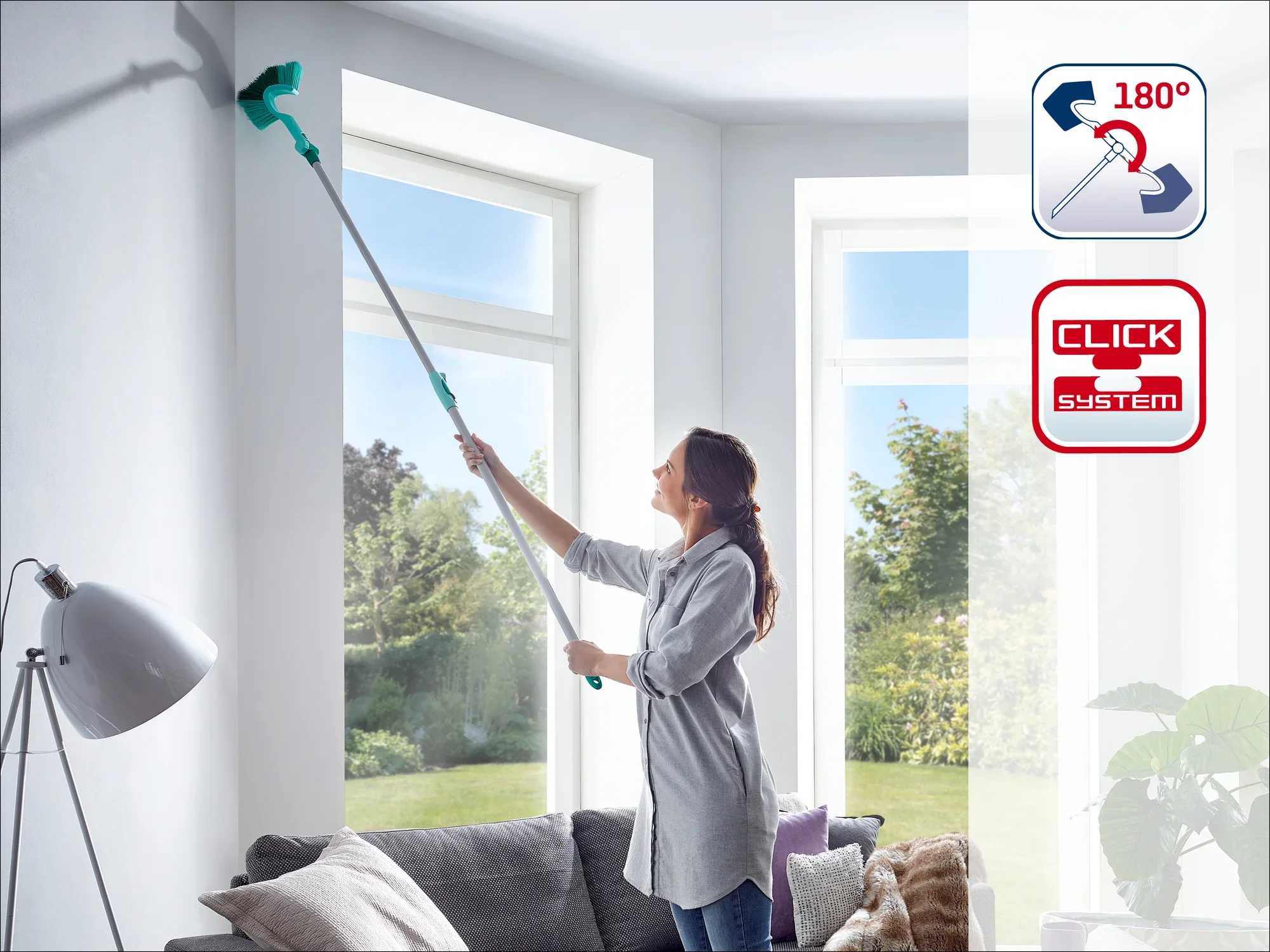 Een vrouw maakt een hoge raamhoek schoon met een Leifheit raamwisser met telescopische steel. De zuigmond heeft een scharnier van 180 graden. Ideaal voor moeilijk bereikbare plaatsen.