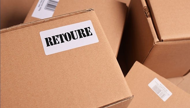 Karton mit "Retour"-Aufkleber stapelt sich mit anderen Paketen in hellbrauner Verpackung, alle zeigen Versandetiketten.